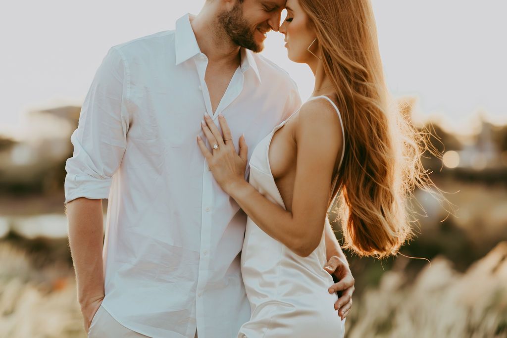 A tender moment between a couple in white clothing during golden hour.