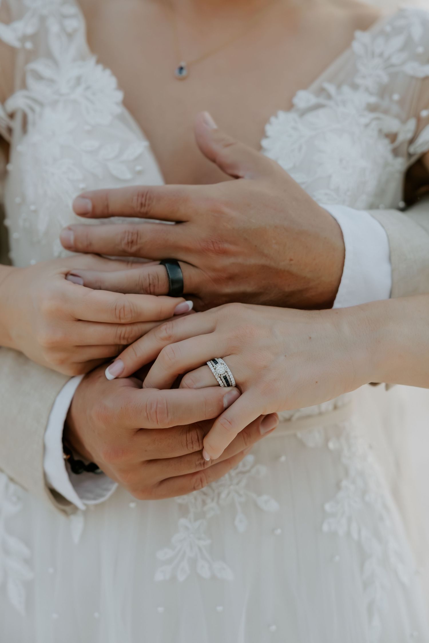 Close-up sequence of hands exchanging wedding rings with lace dress detail.