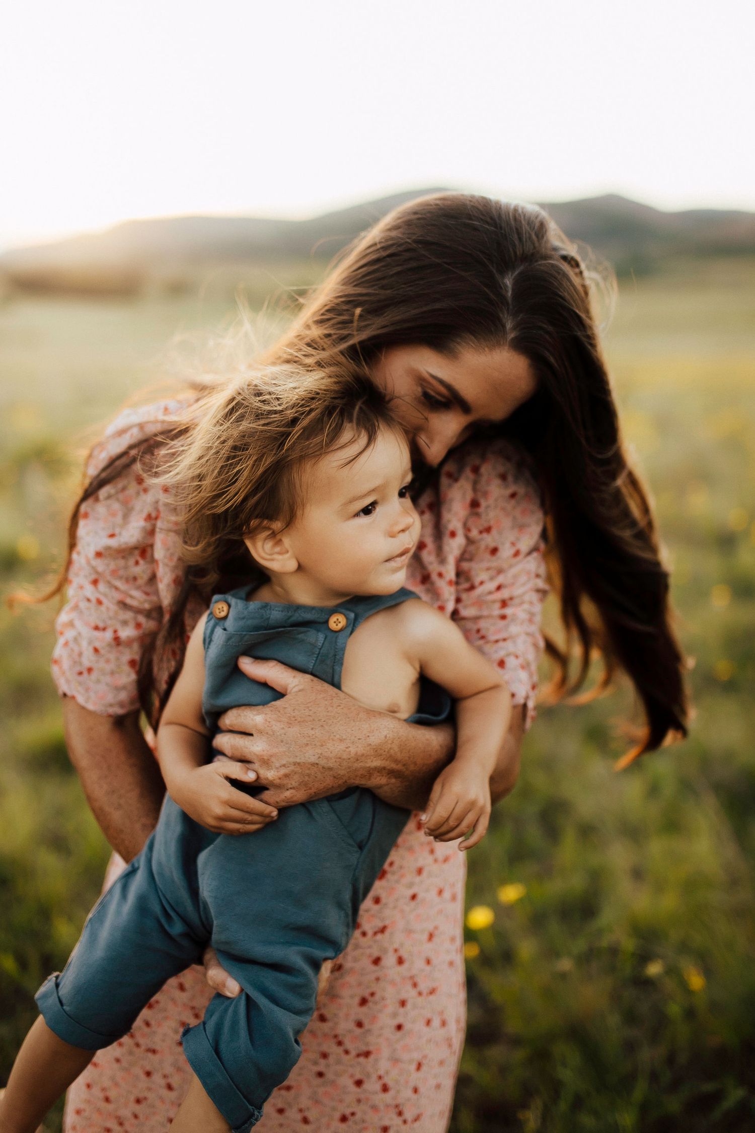 A tender moment captured in a field at sunset showing affection and connection.