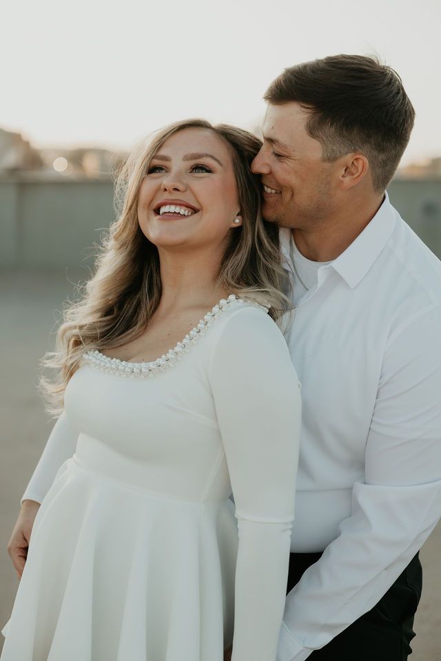 Romantic couple in white outfits share intimate moments during a sunset photo session.