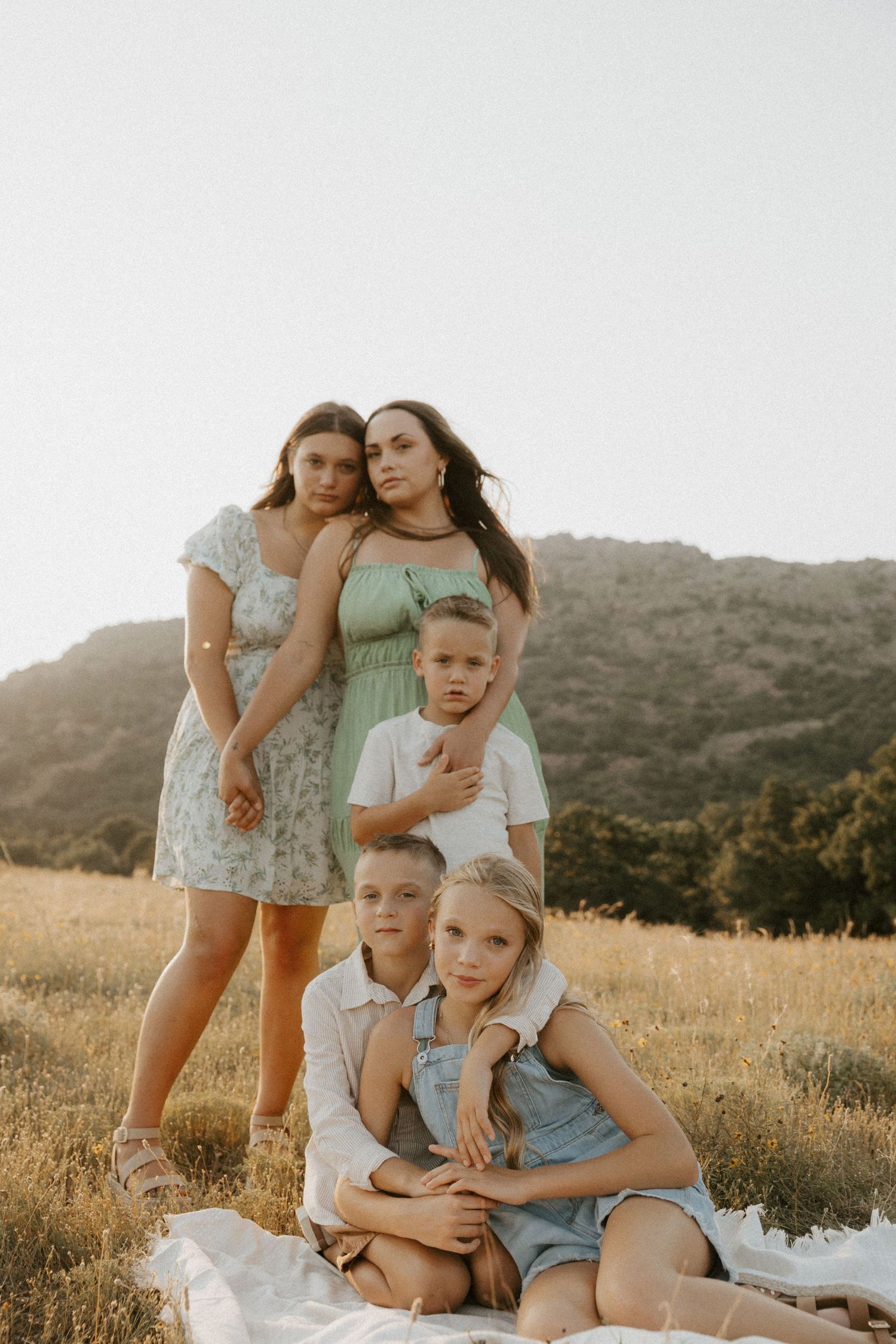 Casual outdoor family portrait session in a golden field at dusk.