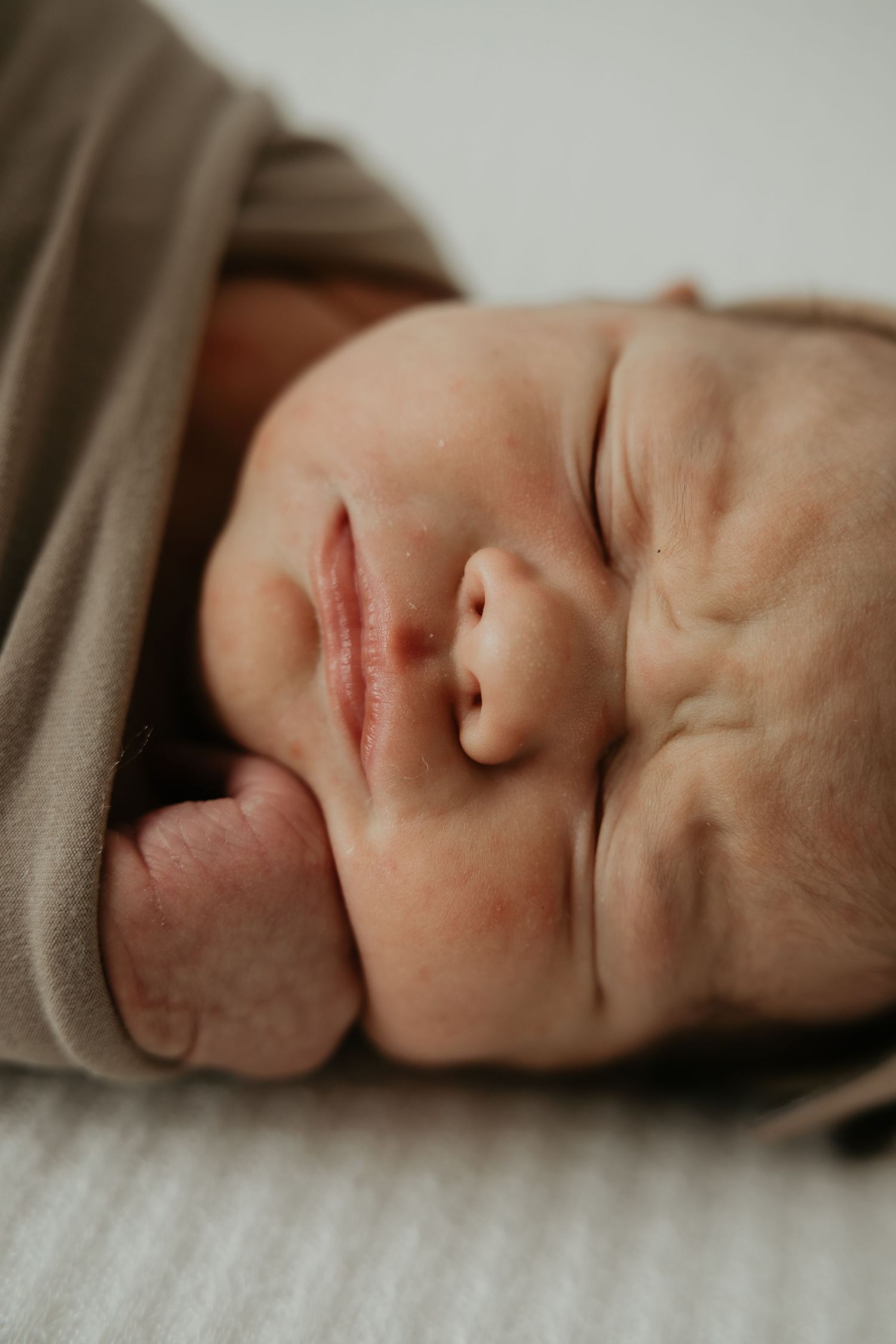 Peaceful sleeping newborn in soft neutral tones photographed in close-up sequence.