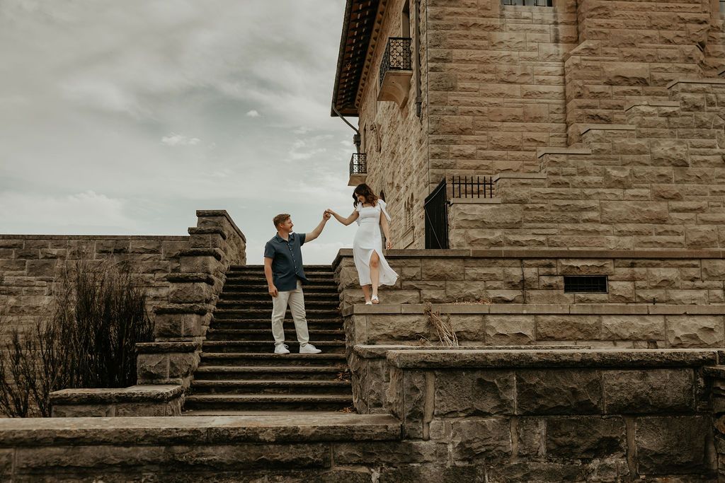 Couple taking photos on stone steps of a historic building.
