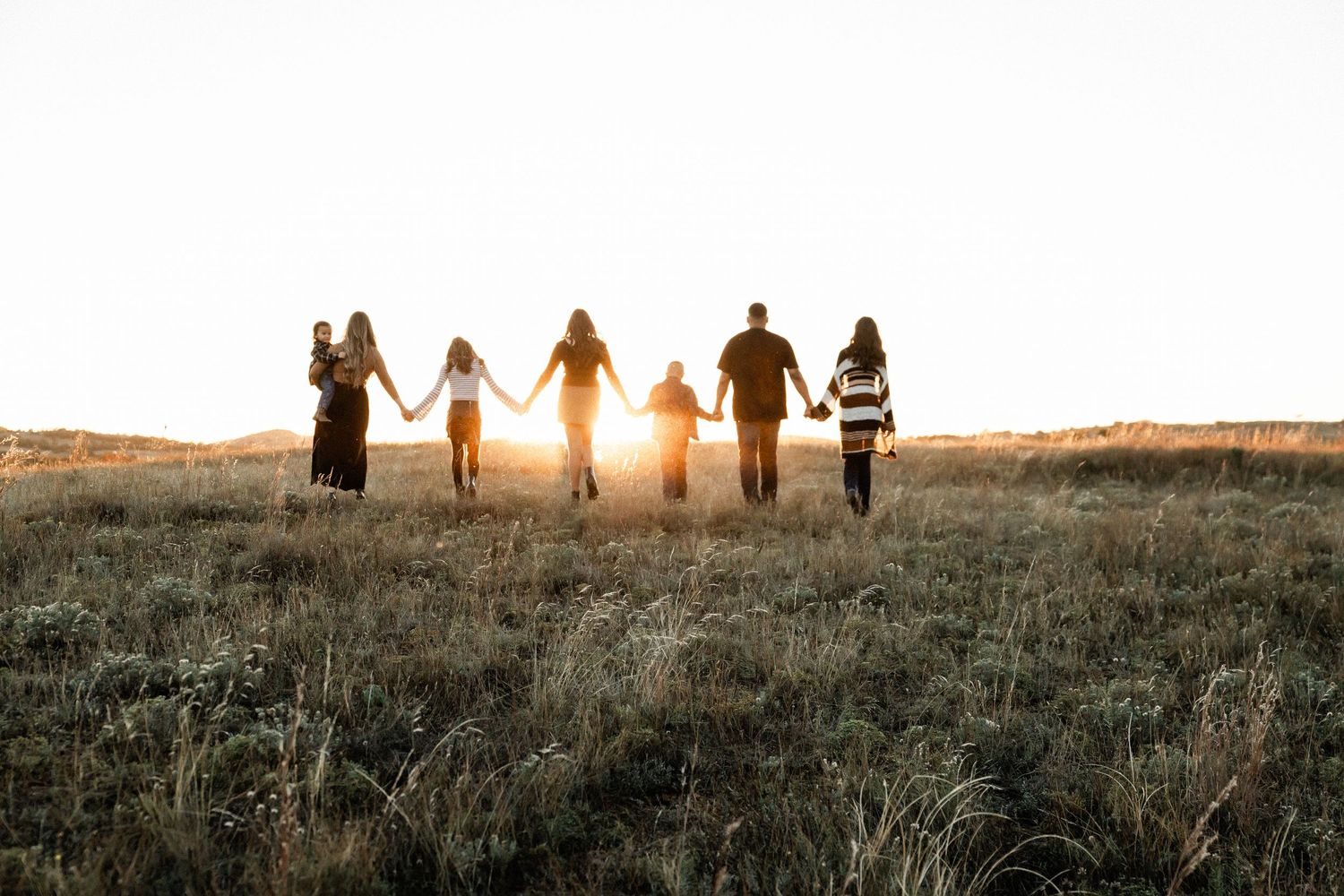 Silhouettes of people walking together against a sunset sky.