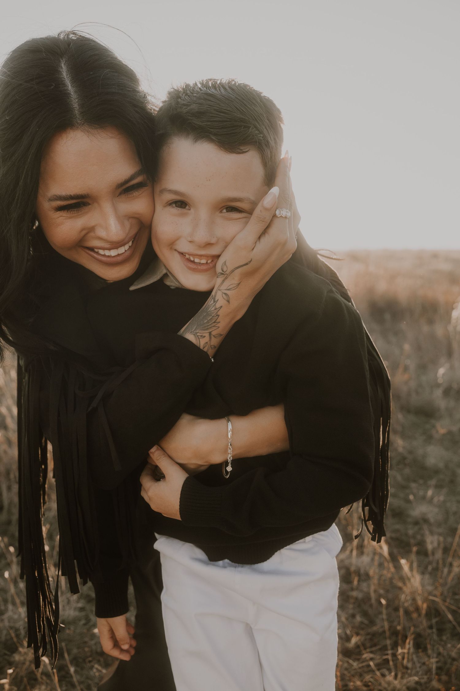 Joyful embrace captured in black clothing against natural outdoor setting.