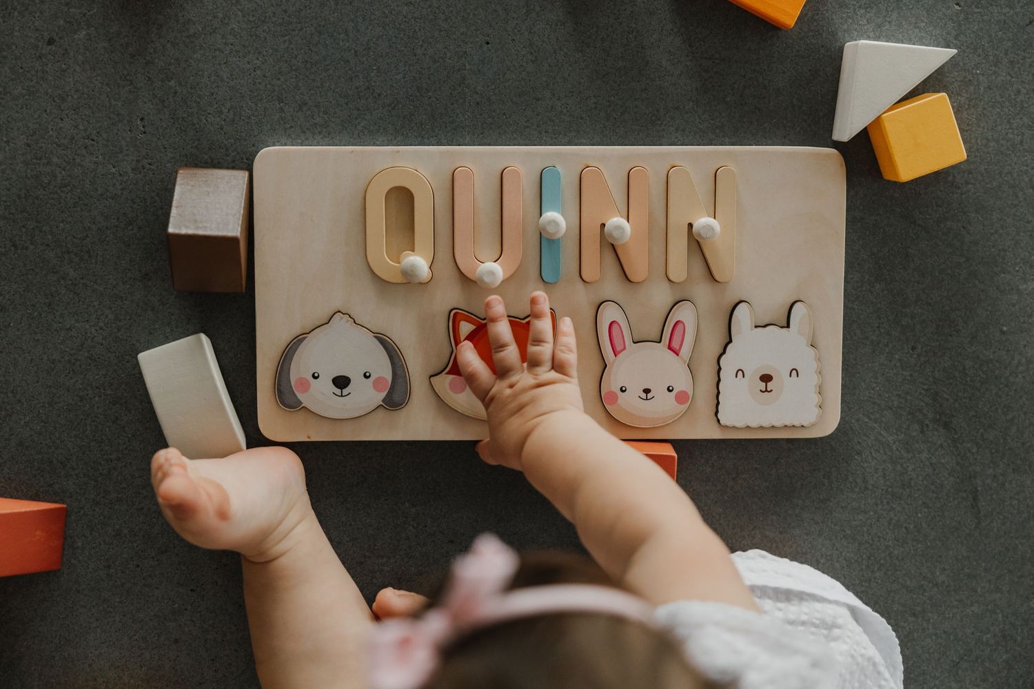 Small hands playing with wooden name puzzle blocks.