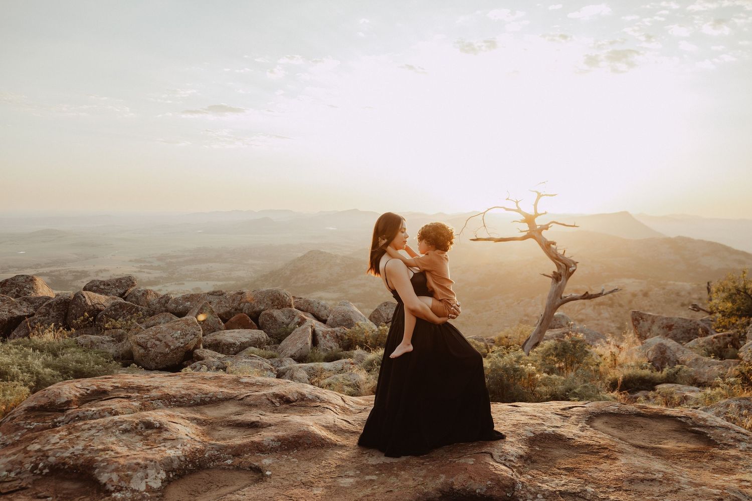 Couple sharing intimate moments on rocky cliffs during sunset.