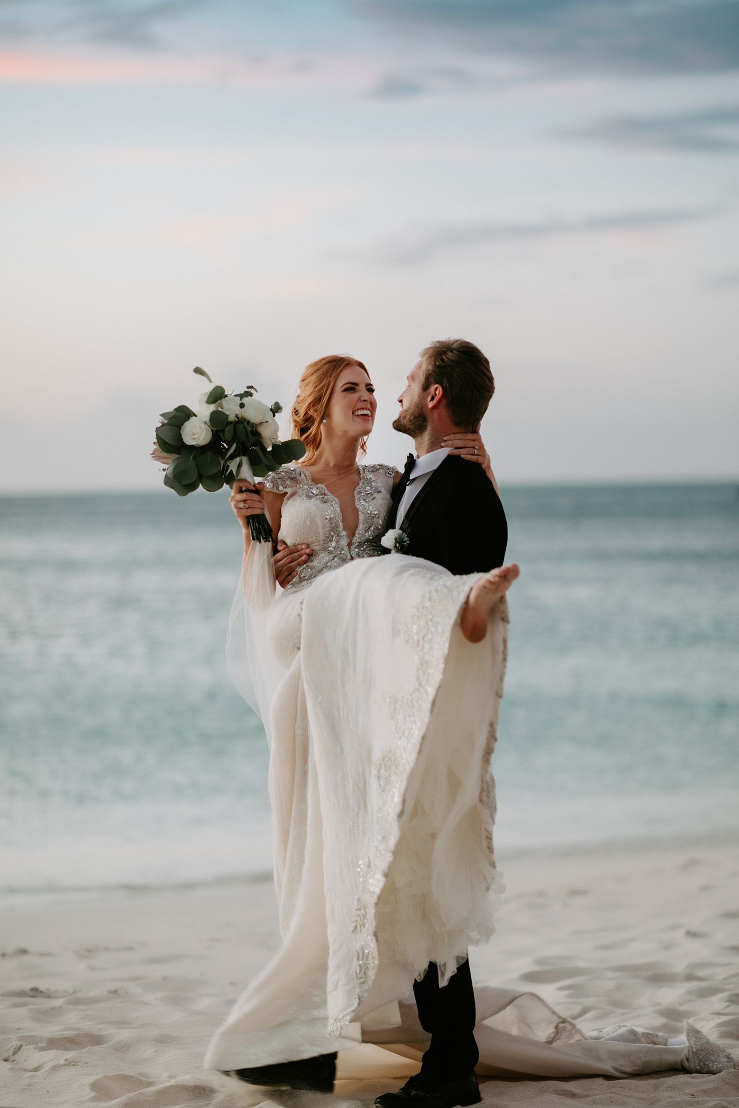 Romantic beach wedding photos with couple against ocean backdrop at dusk.