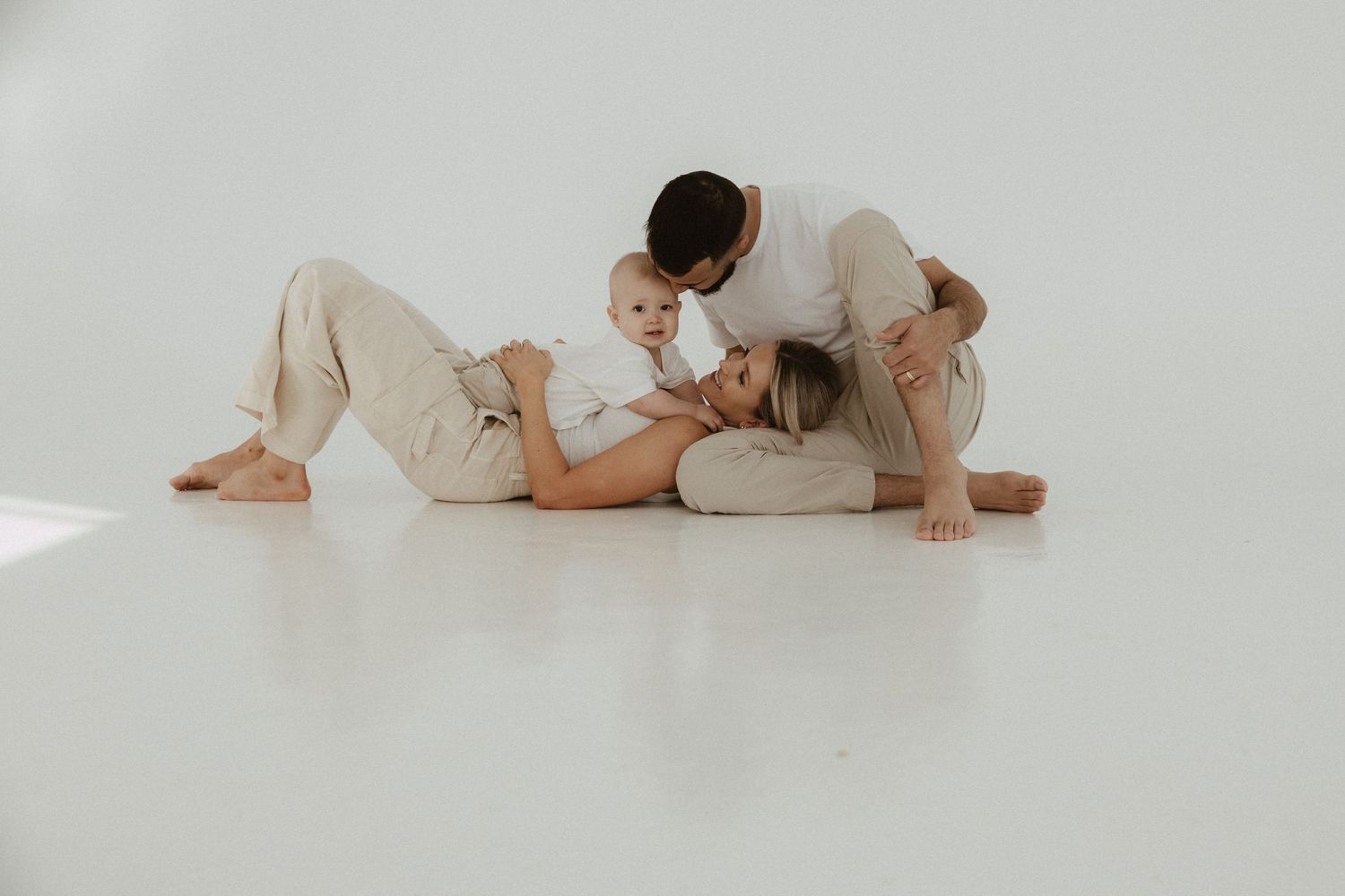 Simple white studio portraits showing intimate family moments on the floor.
