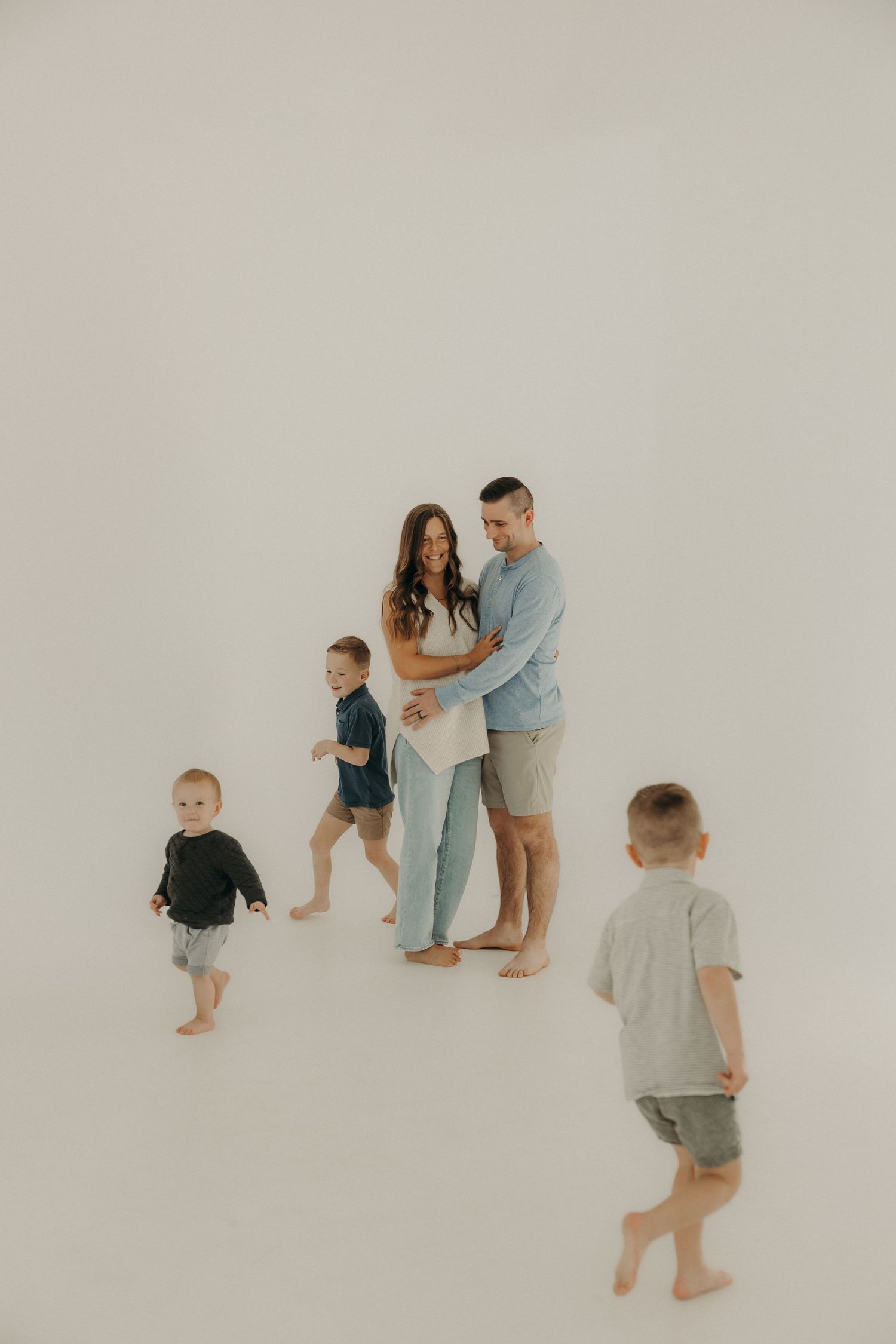 Family members in casual clothing interacting naturally in minimalist white studio setting.