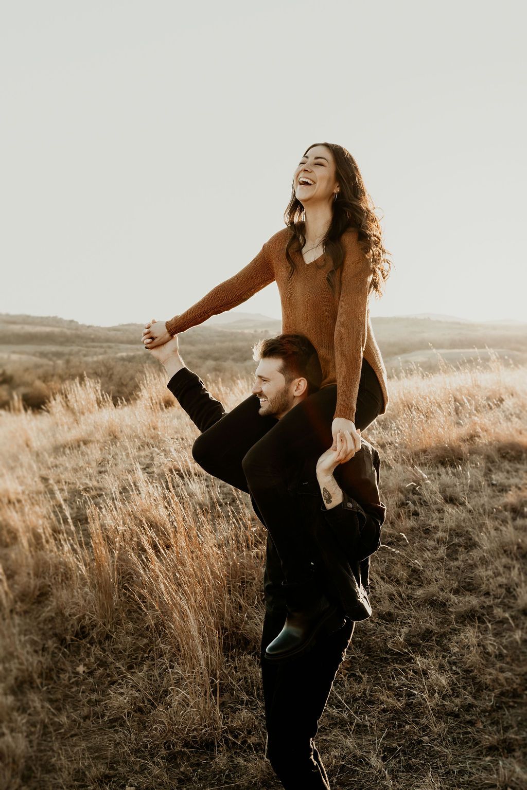 Couple playfully interacting in a golden field at sunset, creating a series of joyful movements.