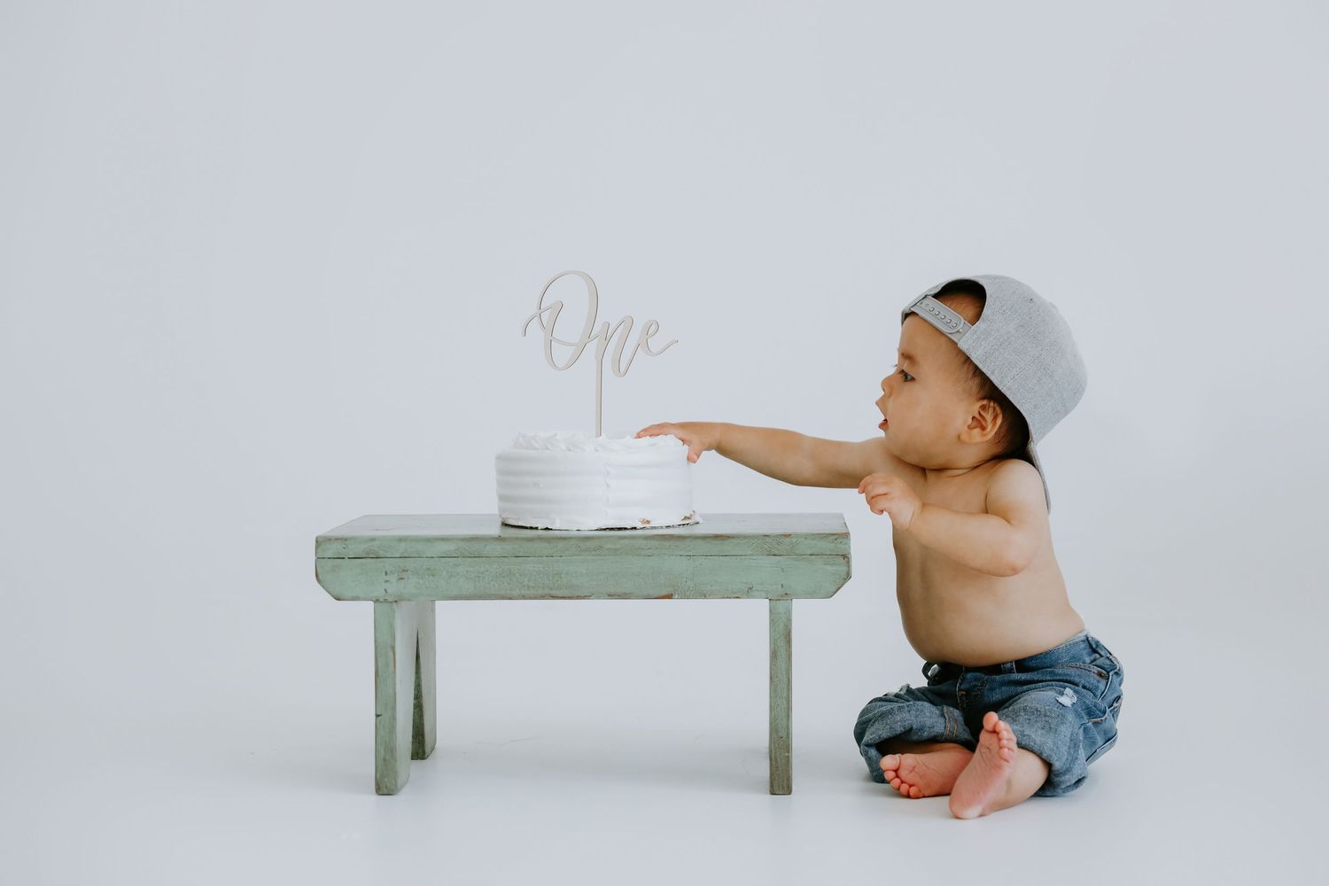 Simple studio photo series with baby on mint green bench.