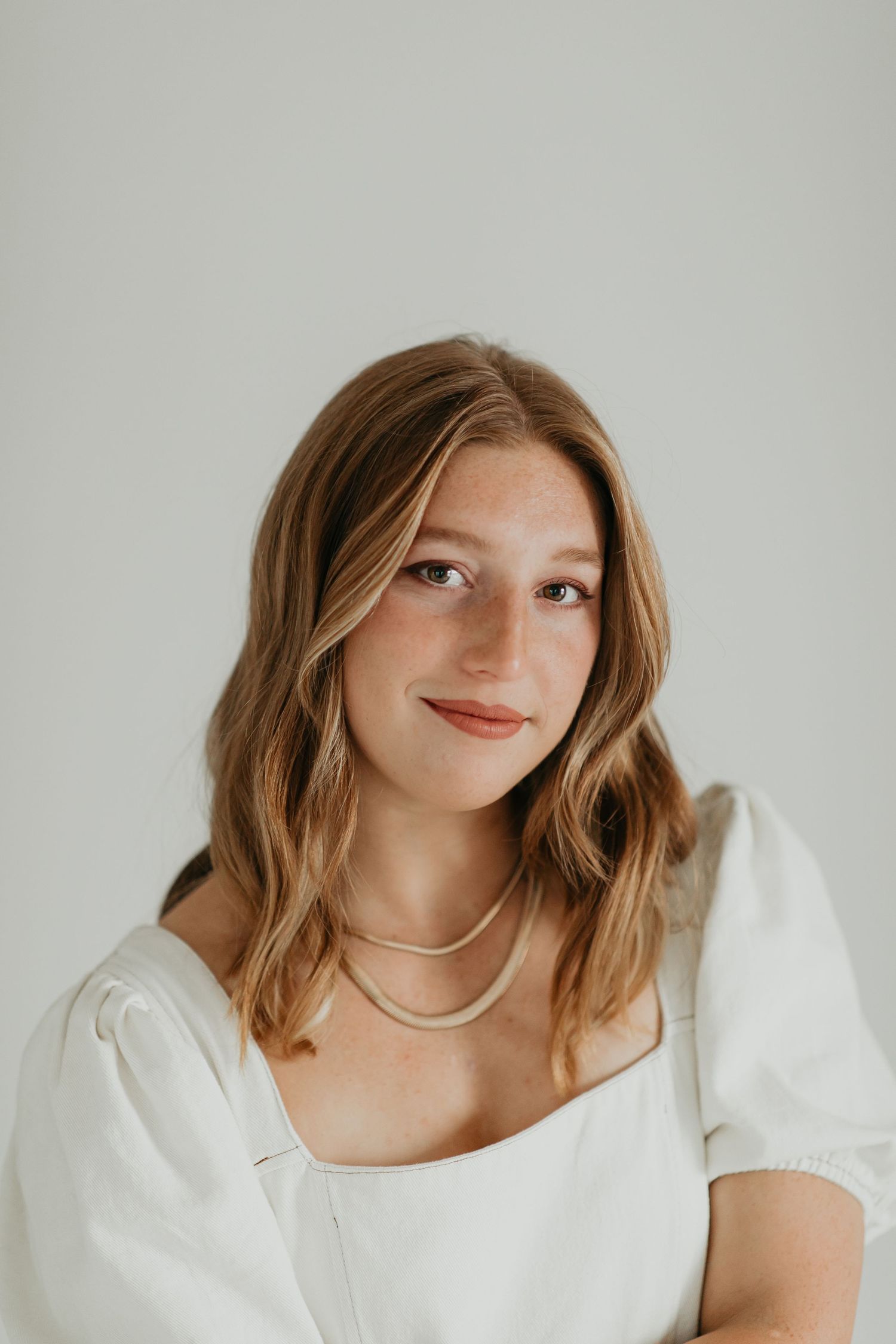 Portrait series in white attire against neutral background showing different poses and expressions.
