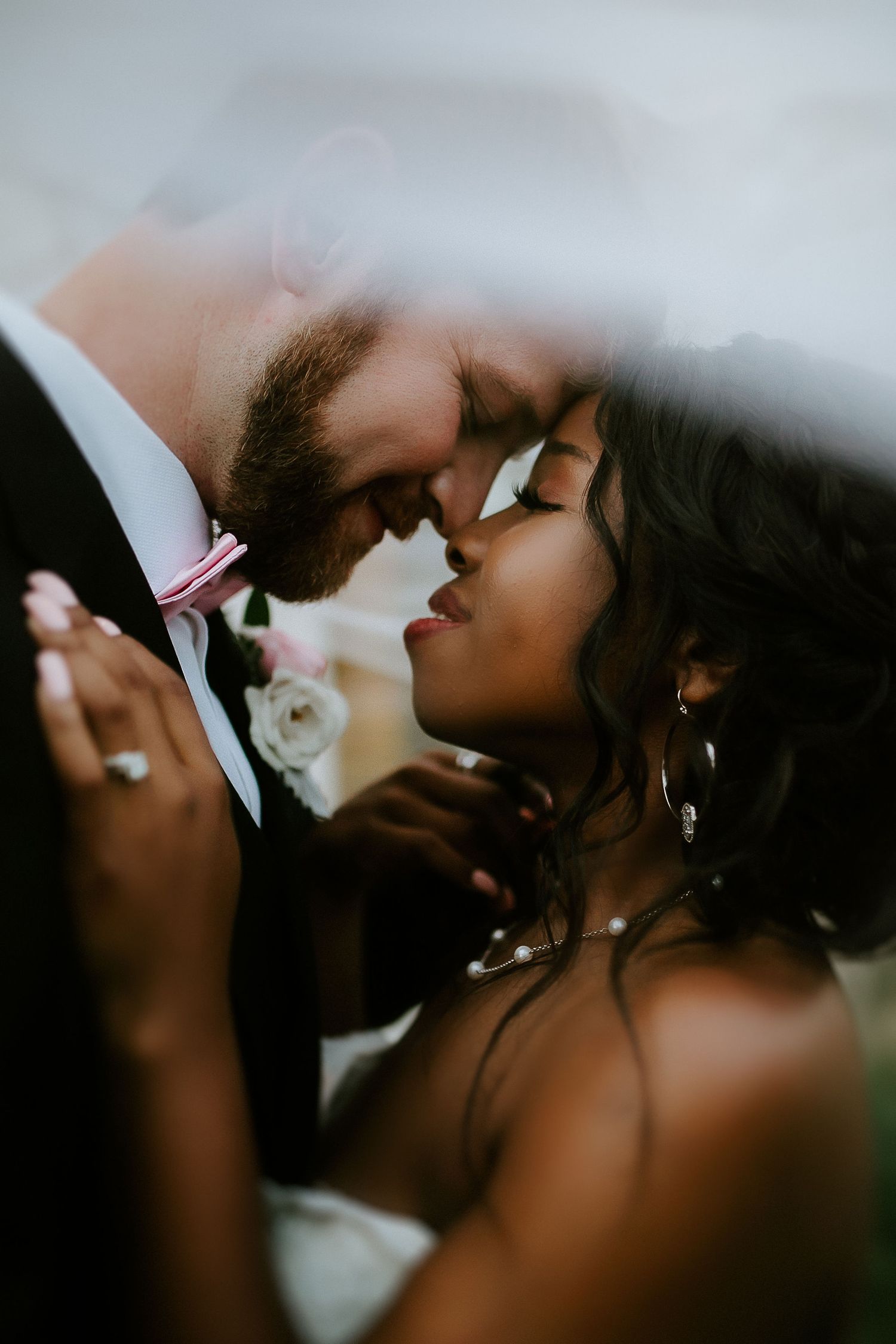 An intimate close-up of a tender wedding moment between two people sharing a romantic embrace.
