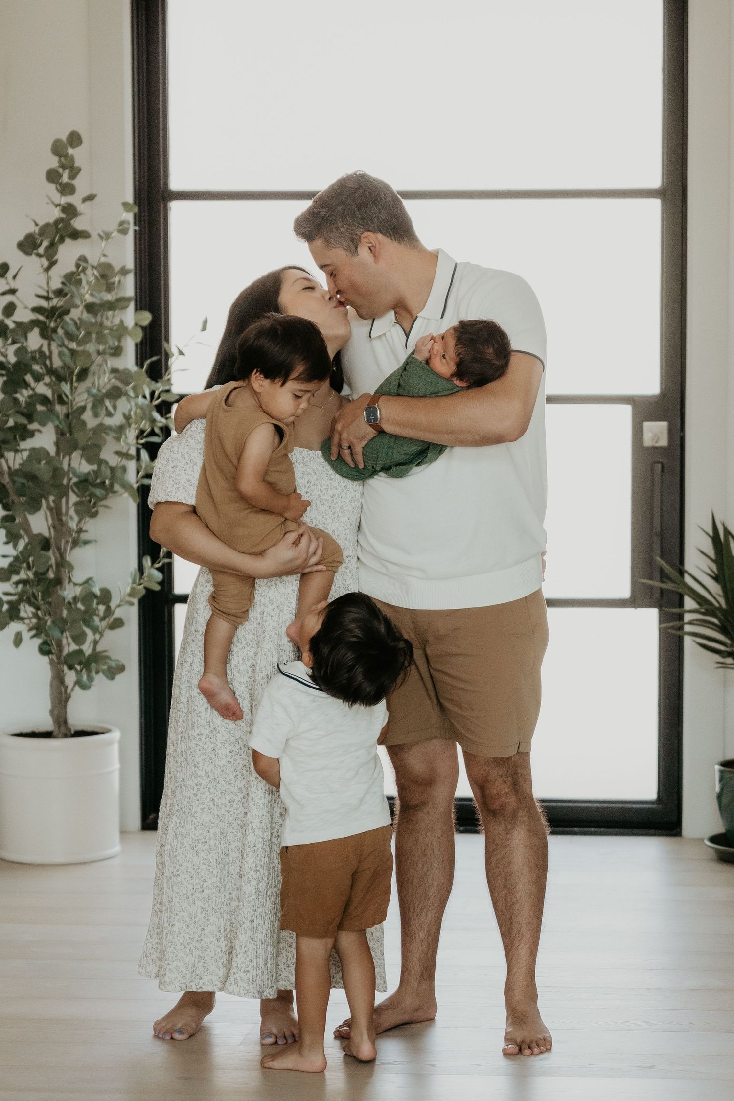 Family sharing tender moments together in bright modern room with plants.