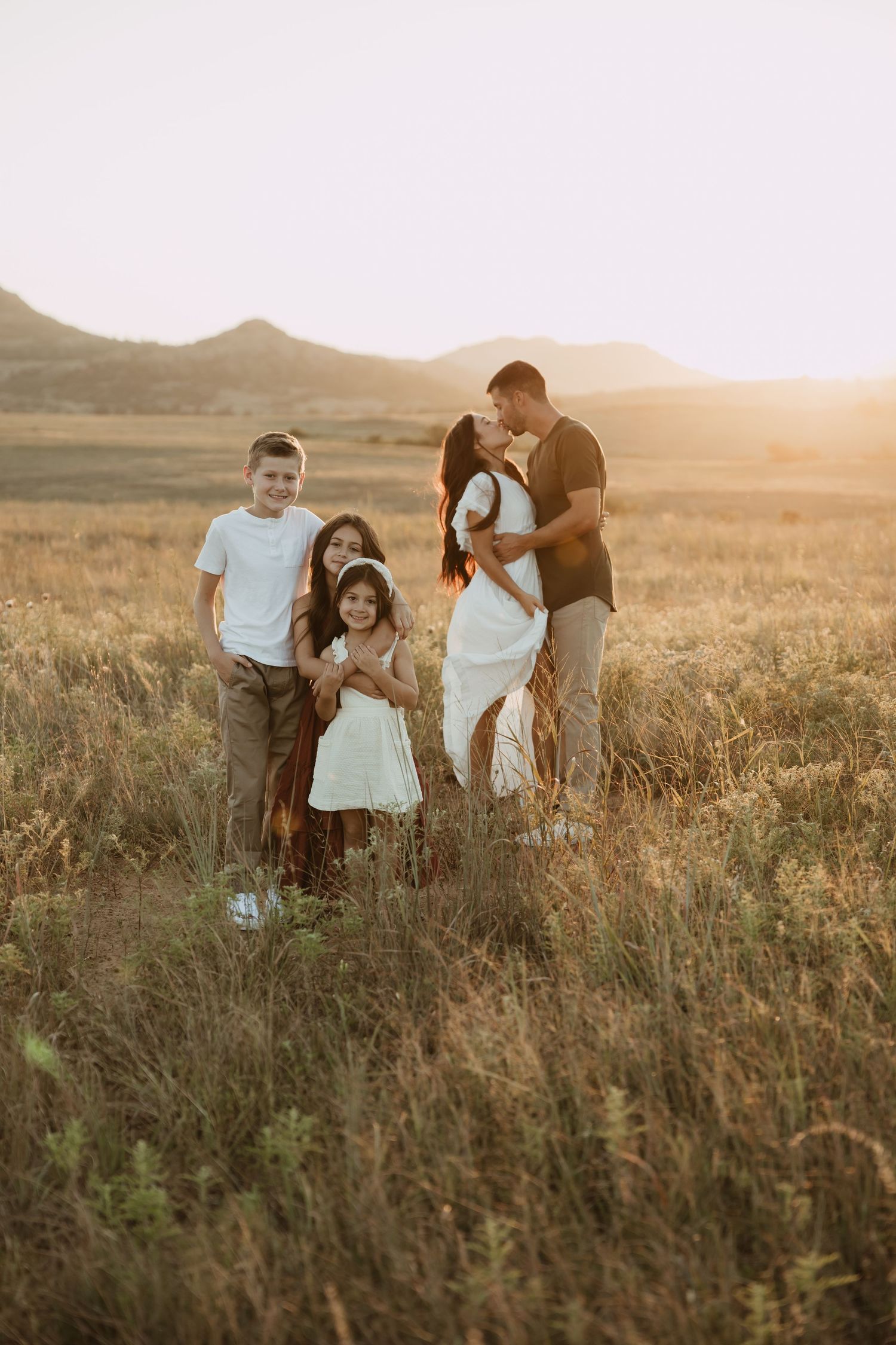 Family enjoying a sunset moment together in a golden field of tall grass.