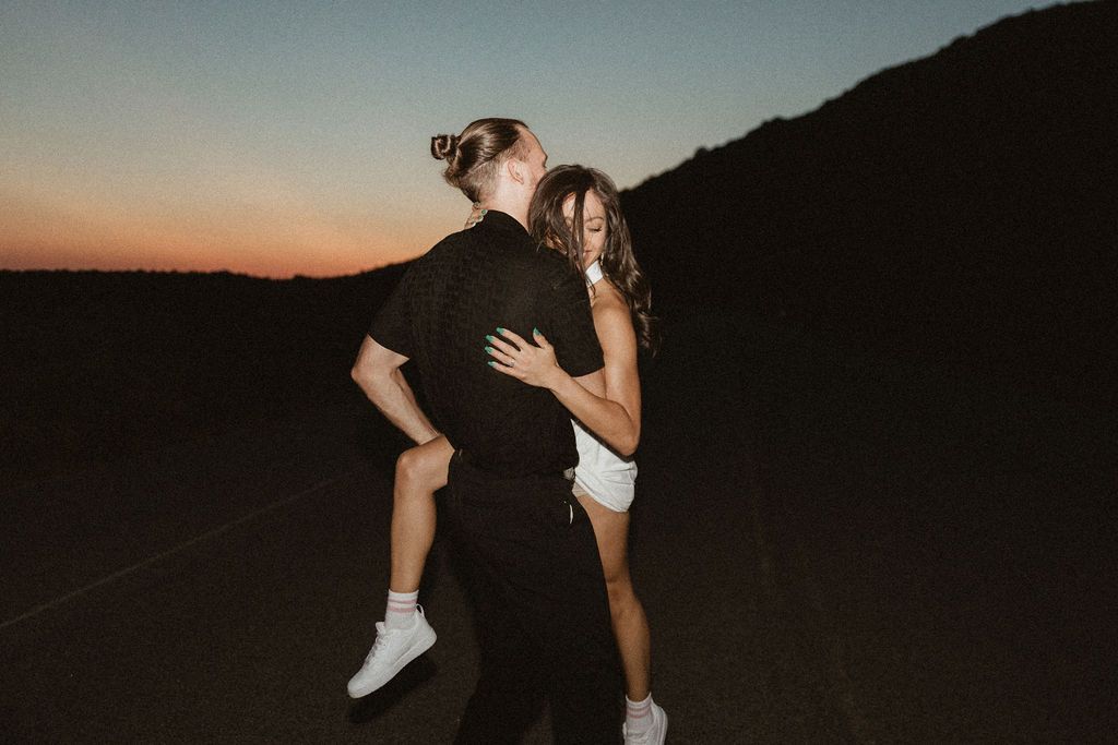 Silhouetted couple dancing in twilight against mountain backdrop.