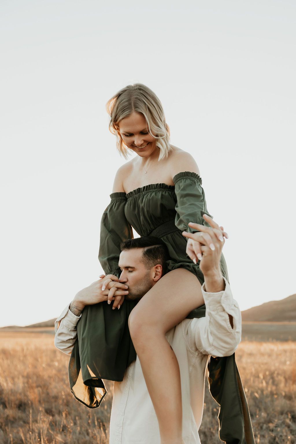 Romantic couple embraces intimately in a golden field at sunset.