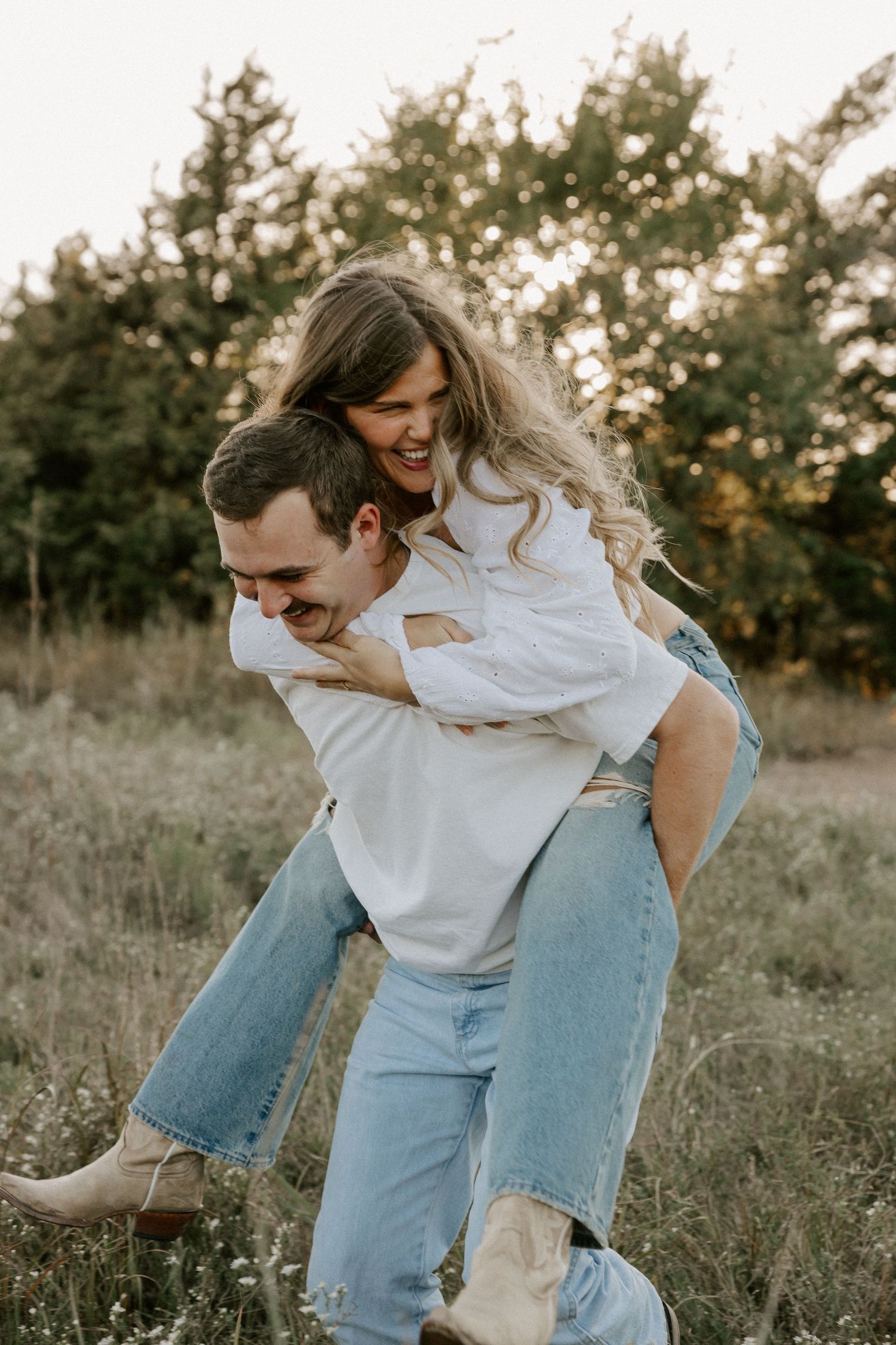 Joyful piggyback ride moment between couple in casual wear at sunset.