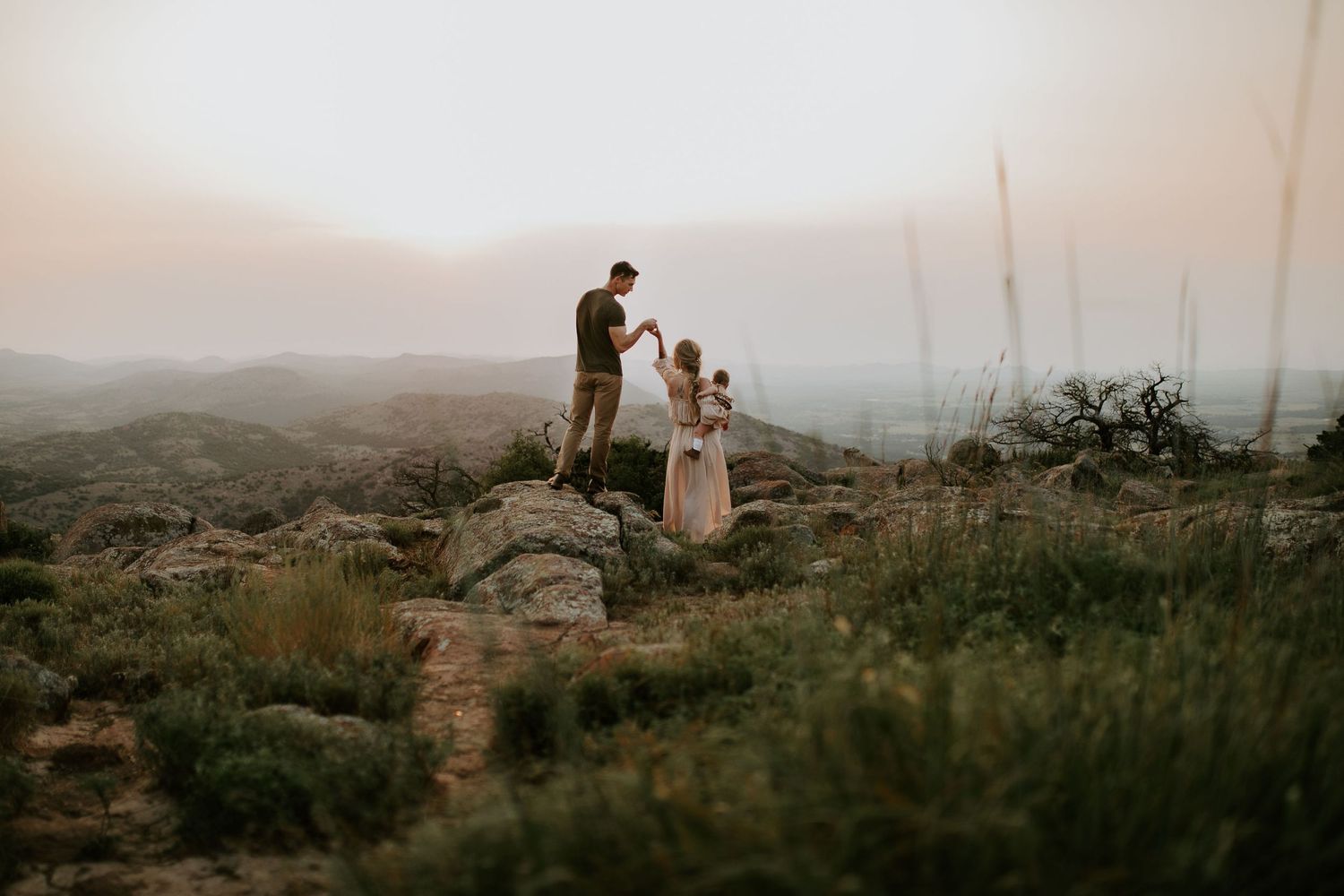 Silhouettes of people standing on a hilltop against a dramatic sunset sky.