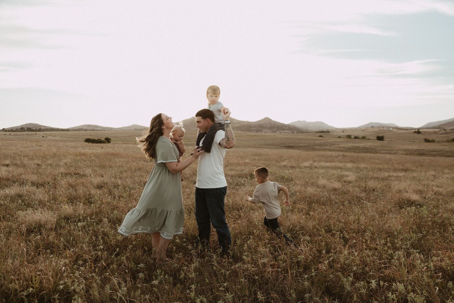 Family walking together through a vast golden field at sunset.