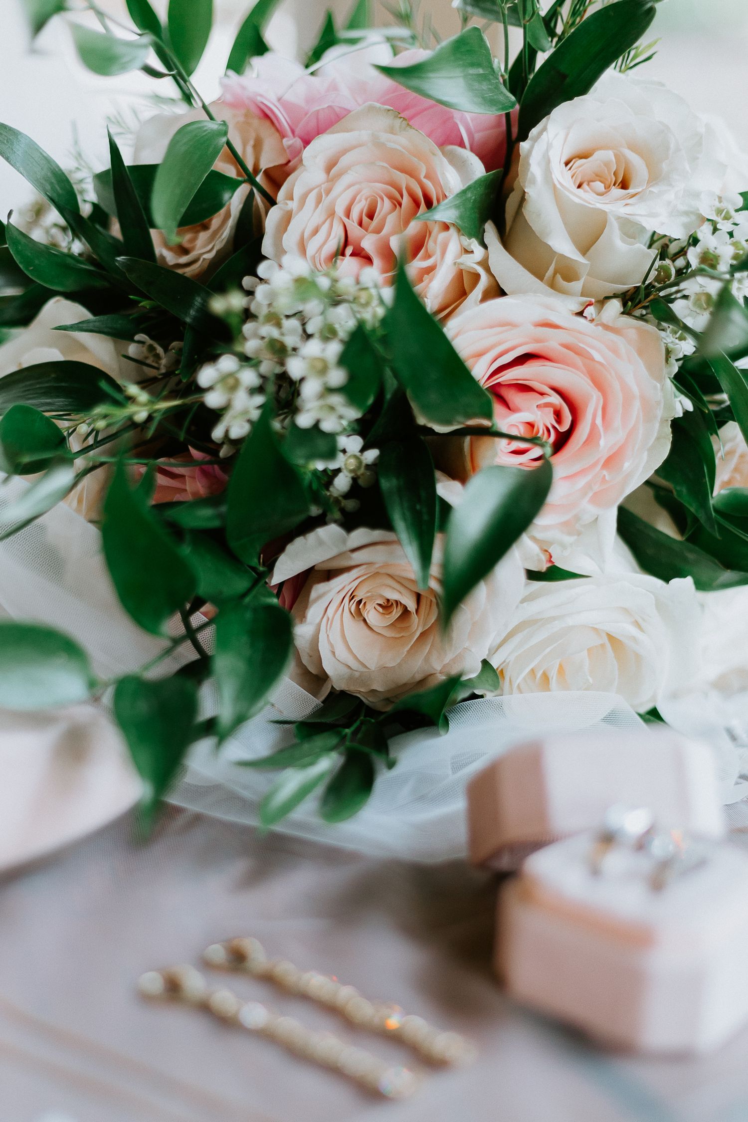 Delicate pink and white roses arranged with green foliage in an elegant wedding centerpiece.