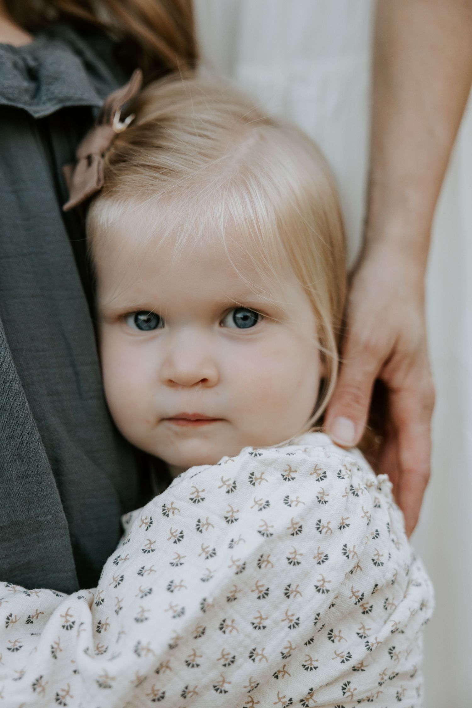 Close-up of baby wearing delicate white patterned dress.