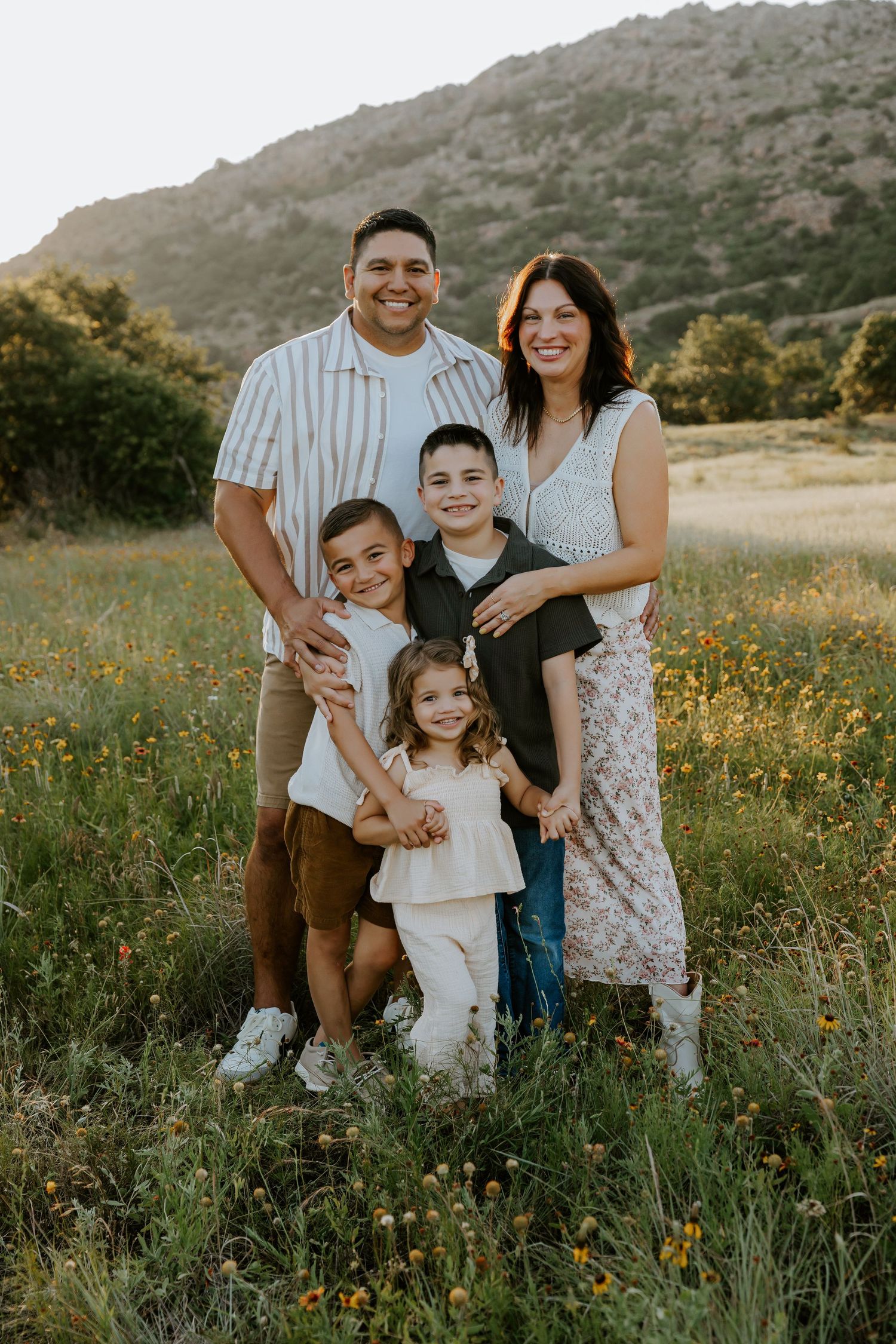 Family portrait session in a wildflower meadow during golden hour.