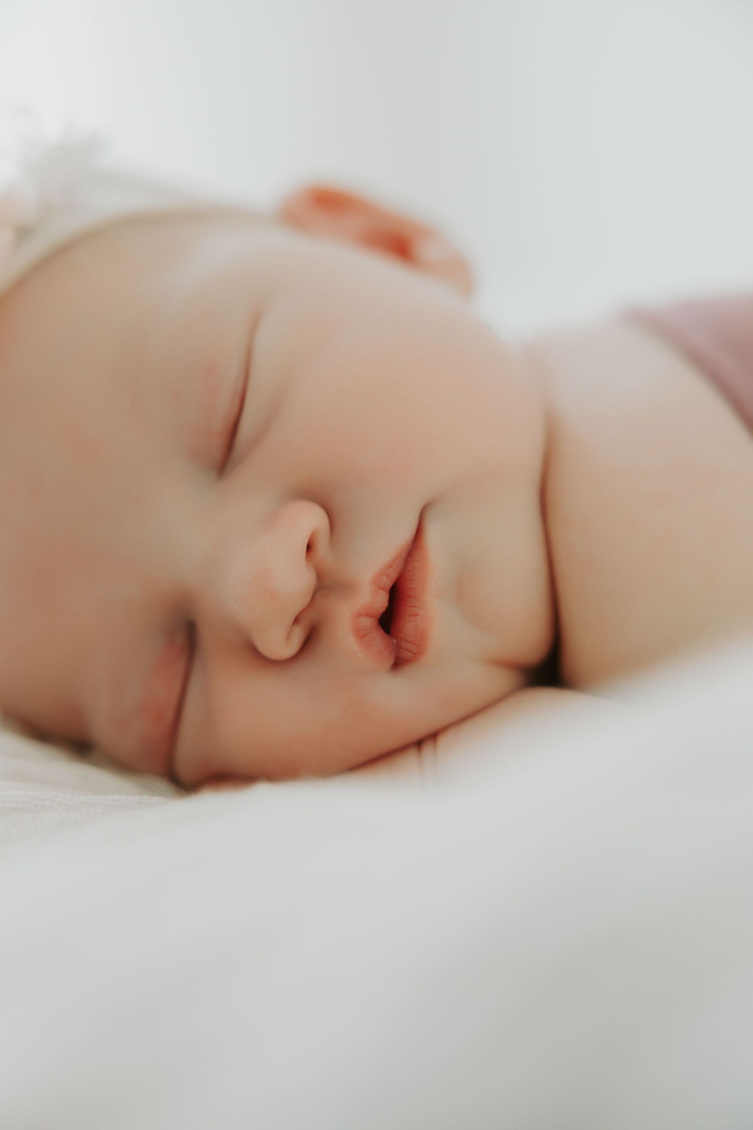 Peaceful sleeping newborn baby swaddled in soft white bedding.