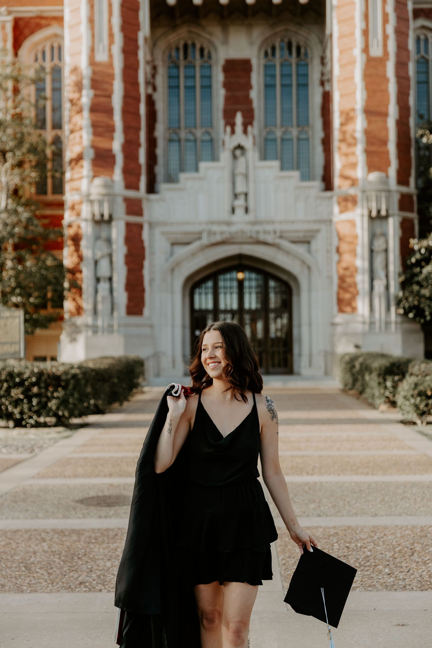 A graduation photoshoot in front of a Gothic-style university building with red brick and white stone details.