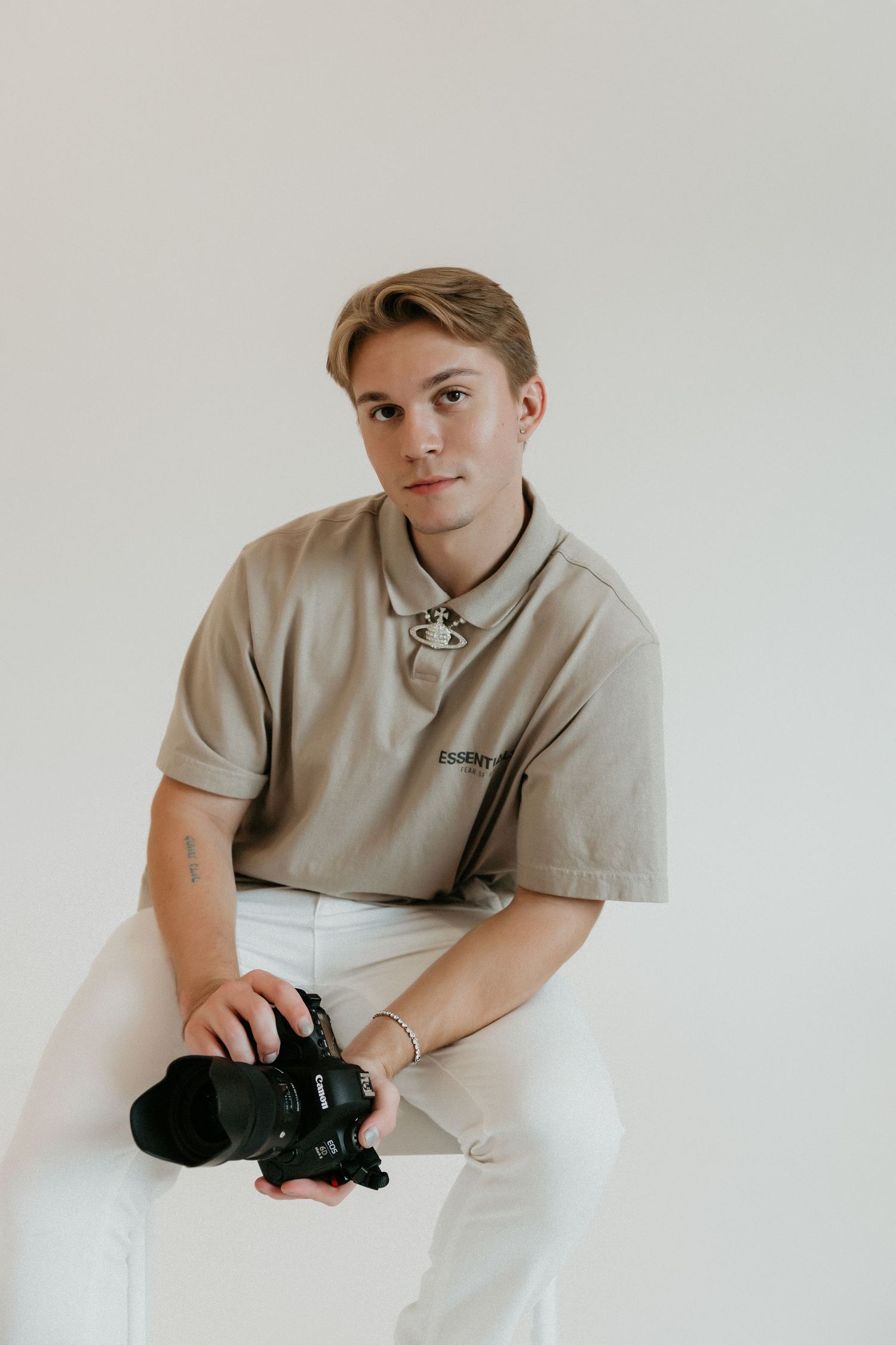 Photographer in beige polo shirt holds camera during studio session.