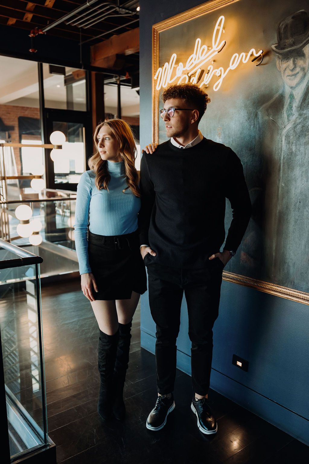 Couple posing together in a modern space with neon lighting and dark walls.