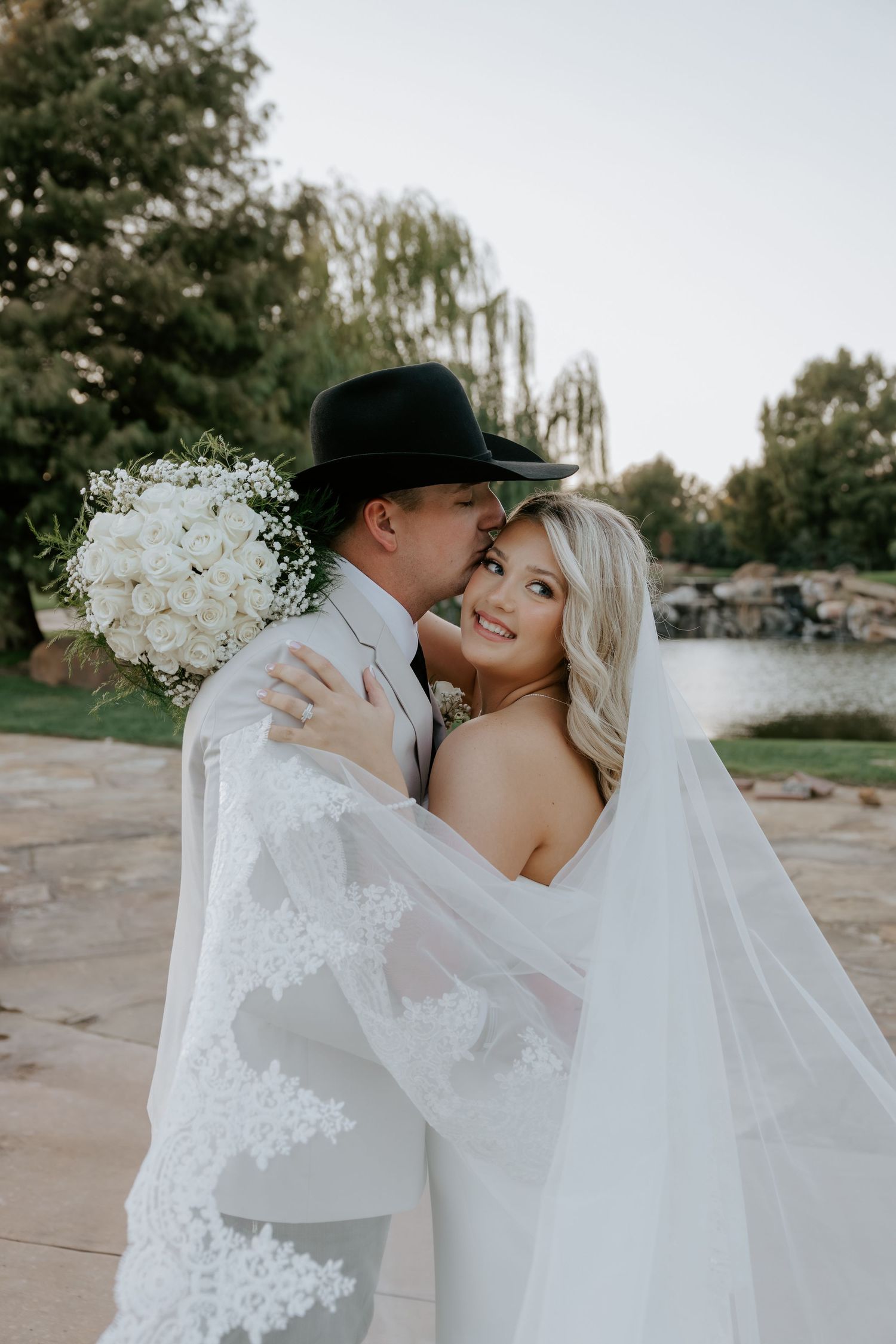 Intimate wedding portraits with flowing white veil against rustic outdoor backdrop.