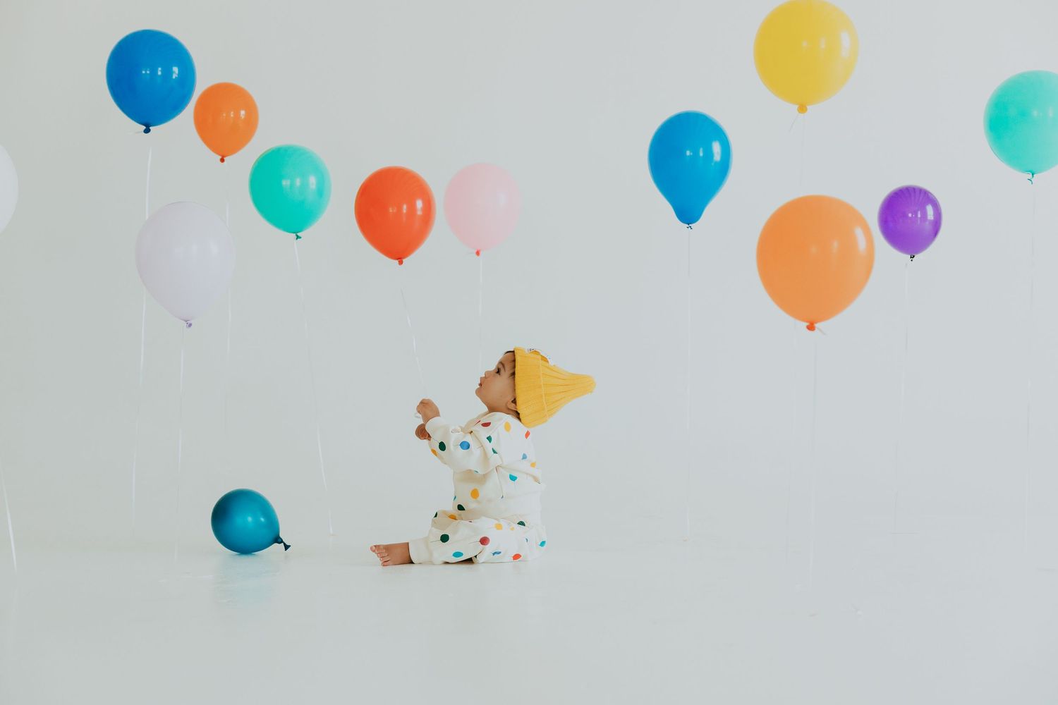 Colorful party balloons float against a light gray background in a festive celebration scene.