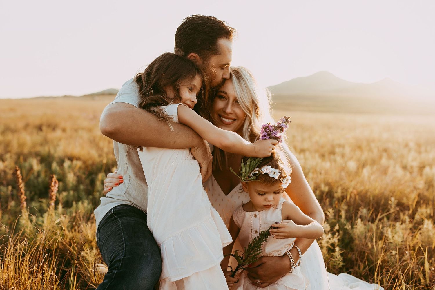 Intimate family portrait session in golden field during sunset.