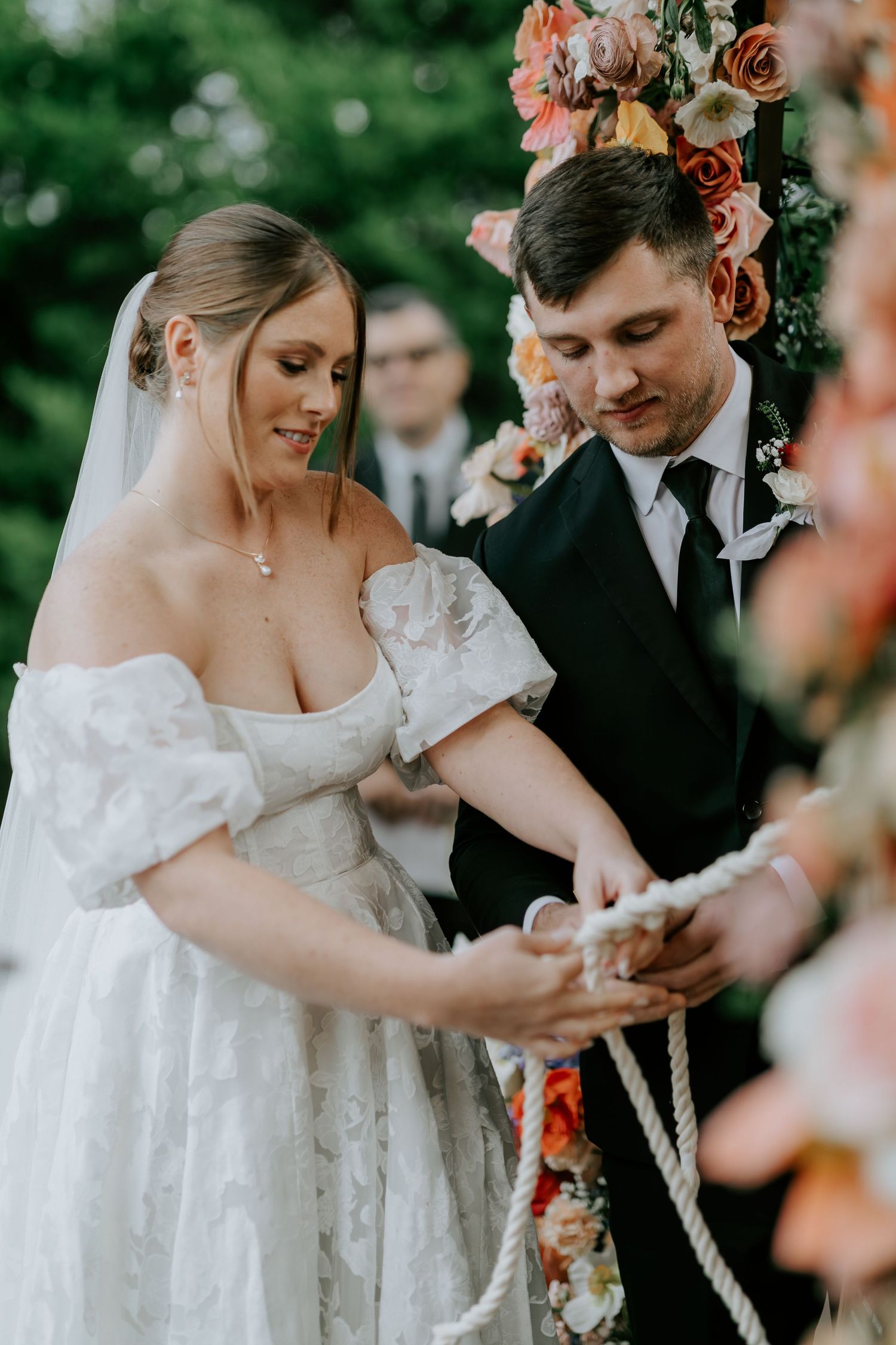 Intimate moments captured during a wedding ceremony with lace dress details and floral accents.