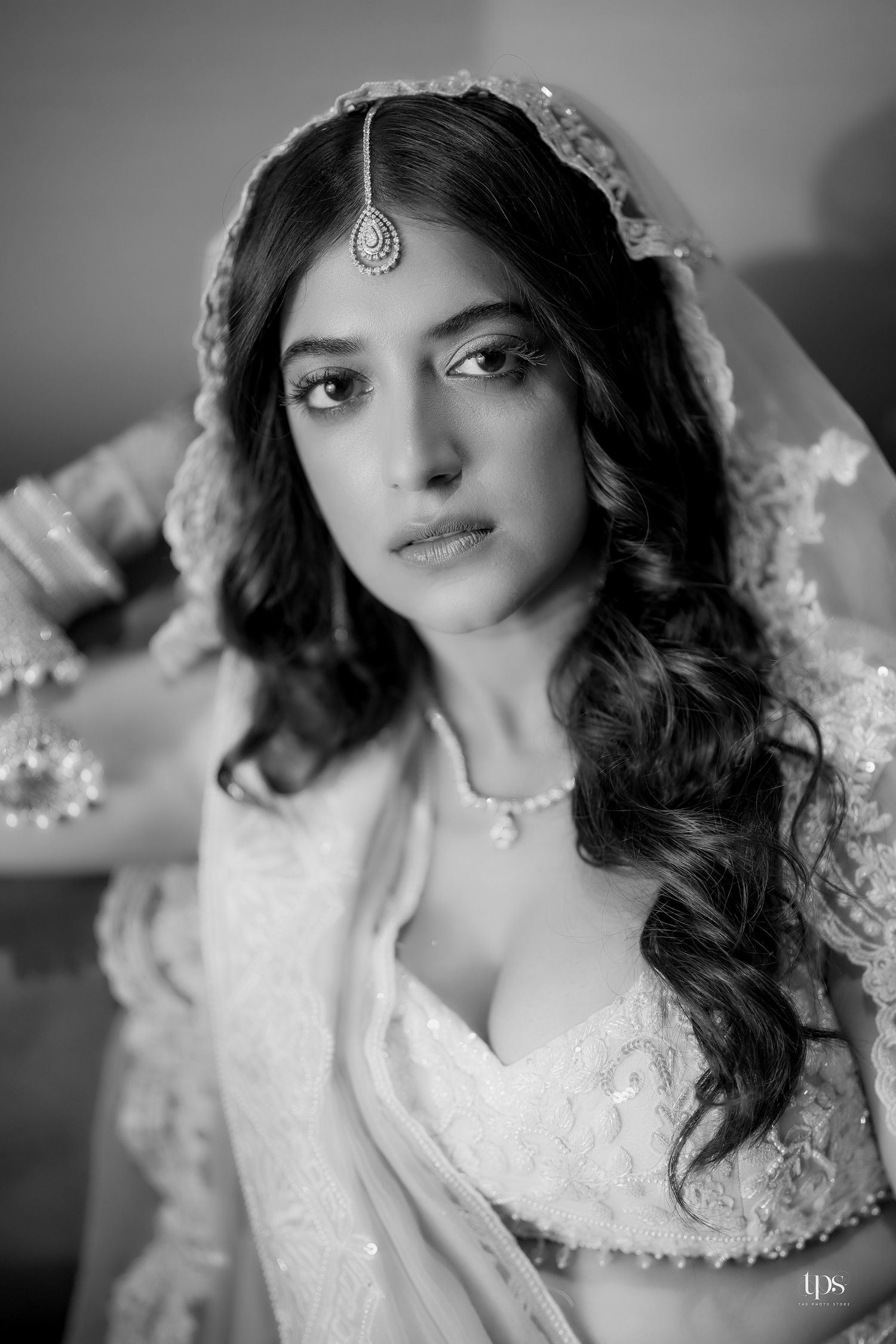 Black and white portrait of a bride in traditional Indian bridal attire with maang tikka and dupatta.