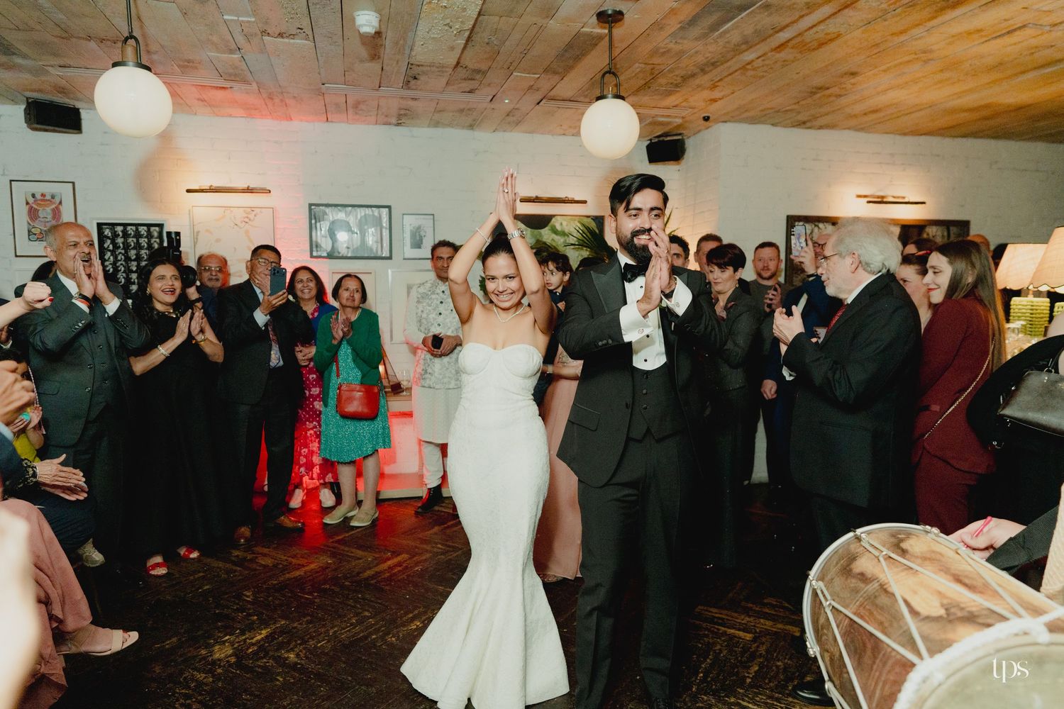 Bride and groom share first dance as guests clap and celebrate at elegant indoor wedding reception.