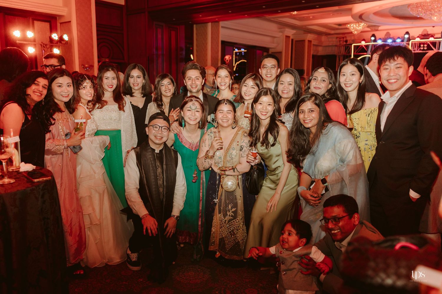 Large group of elegantly dressed guests posing together at a festive formal event or wedding celebration.