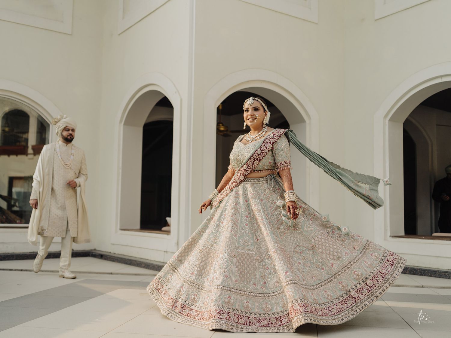 Bride in an ornate lehenga twirling in an elegant white archway, beautifully captured by a wedding Photographer near me in Mumbai