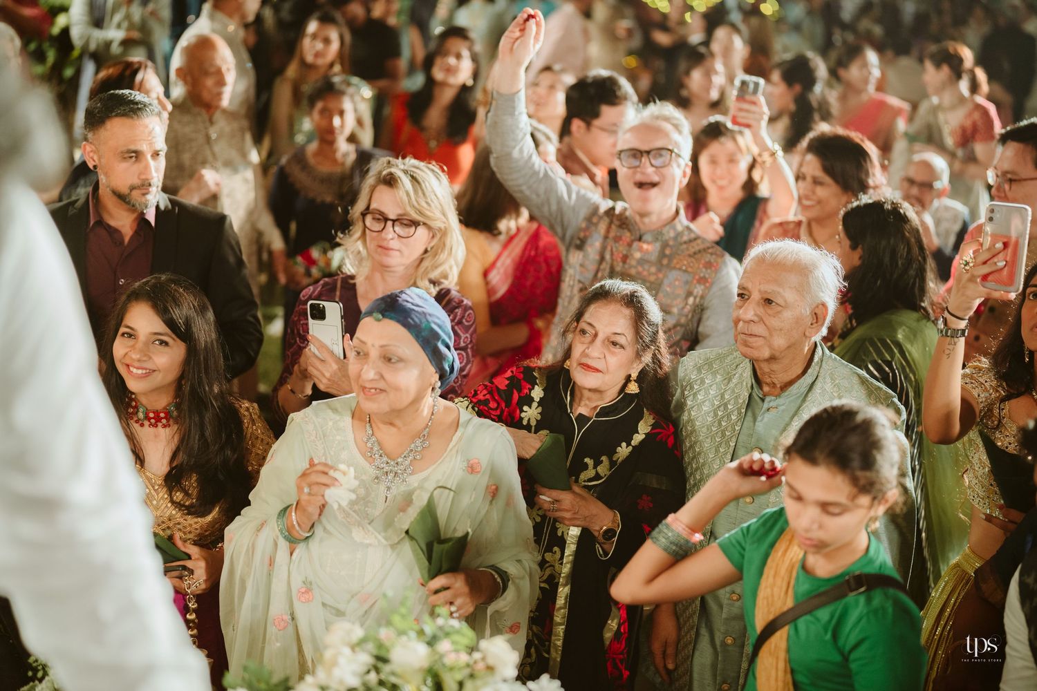 Joyful wedding guests in colorful traditional Indian attire celebrate and dance together at a vibrant wedding ceremony.