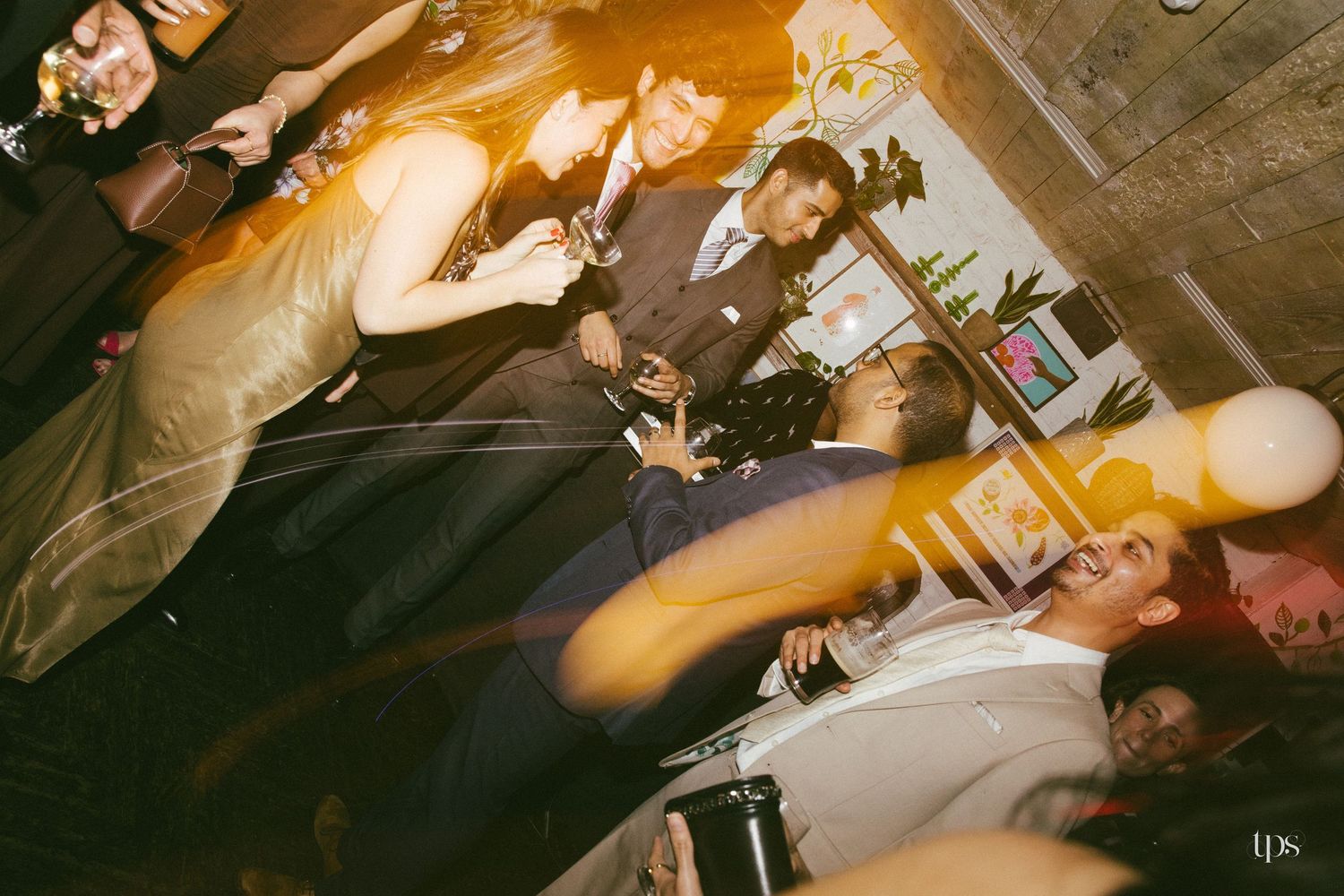 Guests celebrating at an elegant indoor party, laughing and socializing in formal attire under warm ambient lighting.