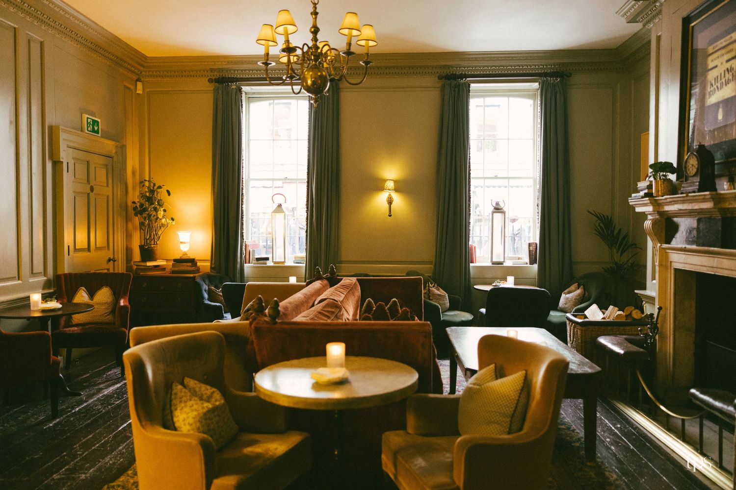 Elegant hotel lounge with gold velvet chairs, chandelier, fireplace, and warm amber lighting in a classic interior.