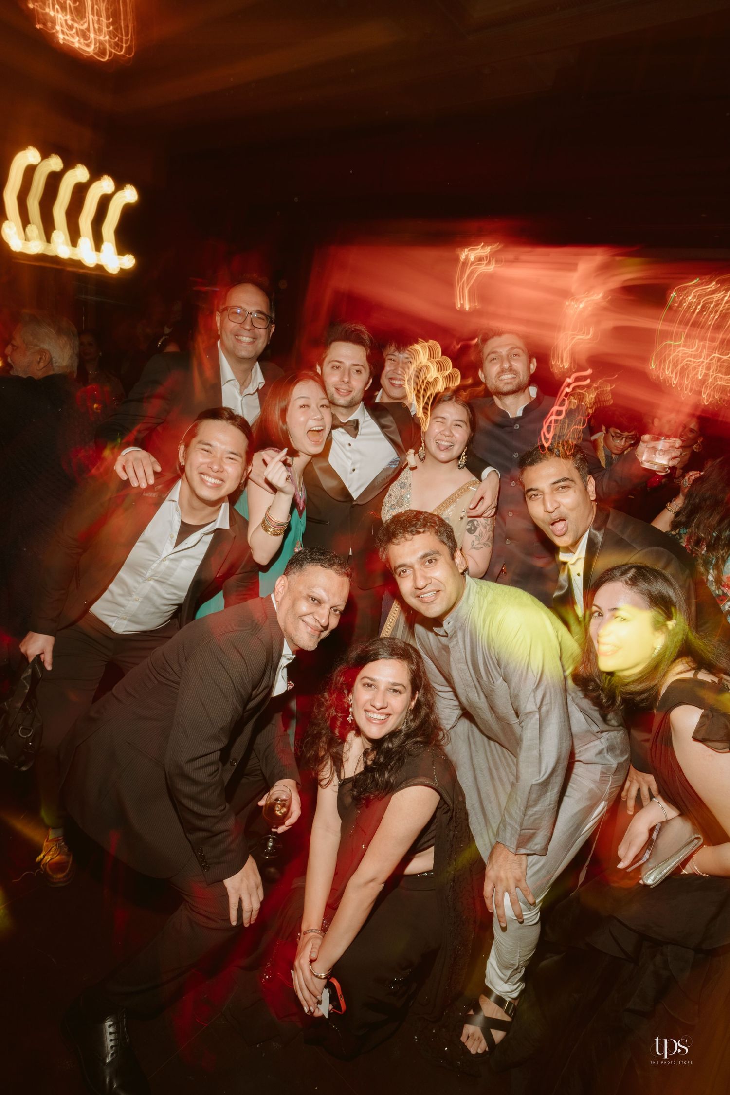 A lively group of elegantly dressed friends posing together on a dance floor at a festive evening party.