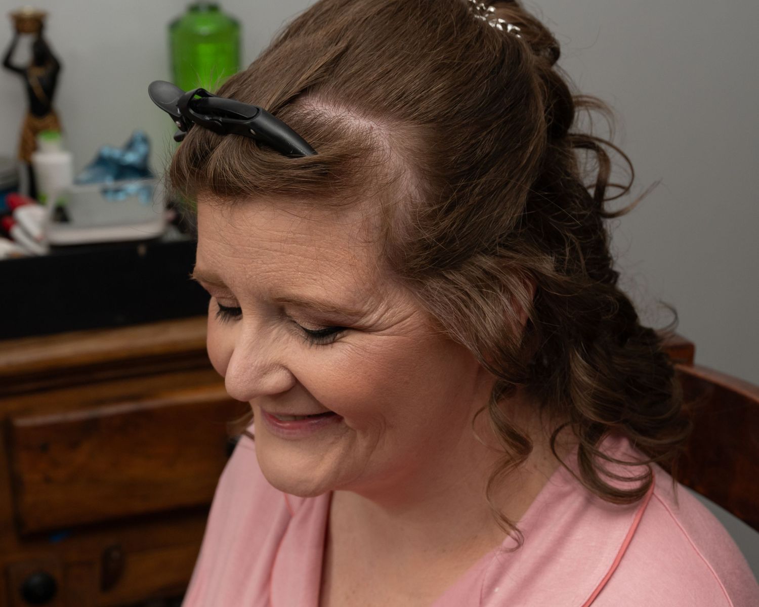 Wedding preparation showing hairstyling in progress with pink attire.