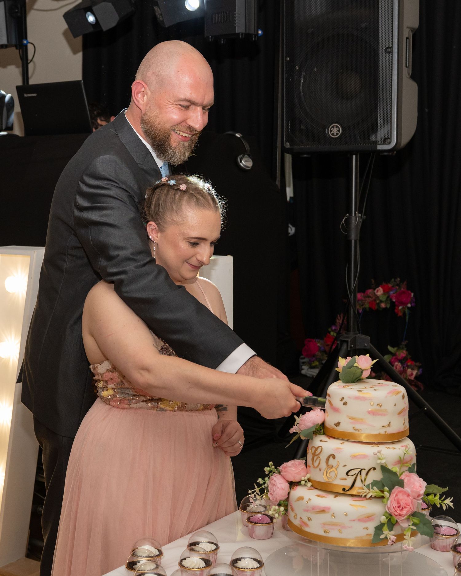 Wedding reception scene showing cake cutting with pink and floral decorations.