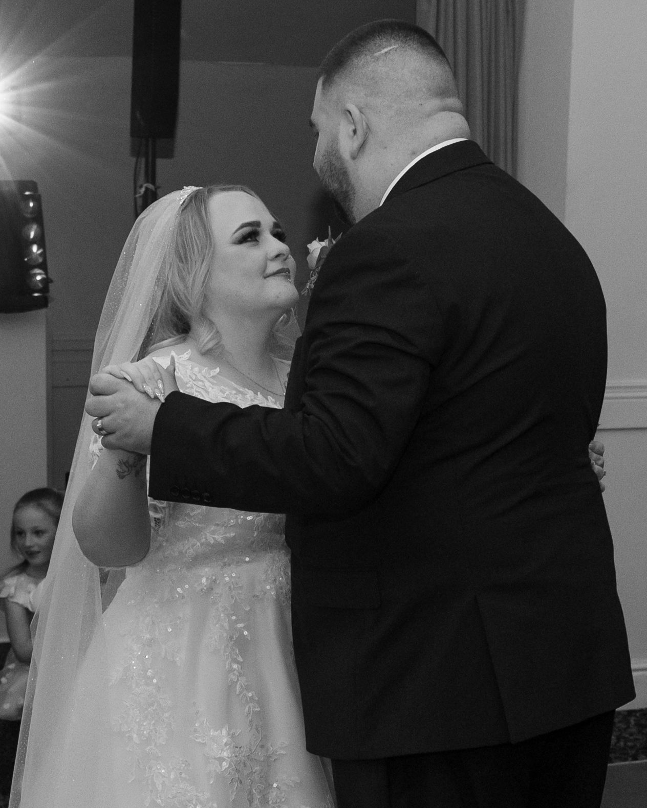 Black and white photo of a bride and groom sharing their first dance at a wedding reception.