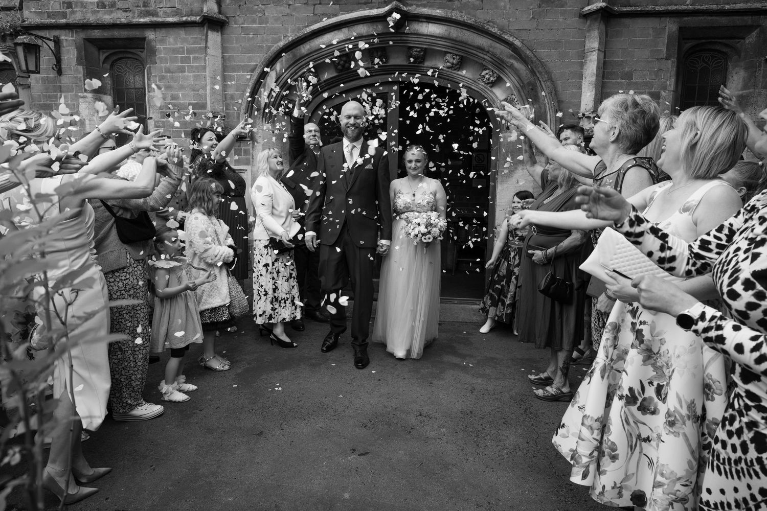 Wedding guests throwing confetti at outdoor celebration.