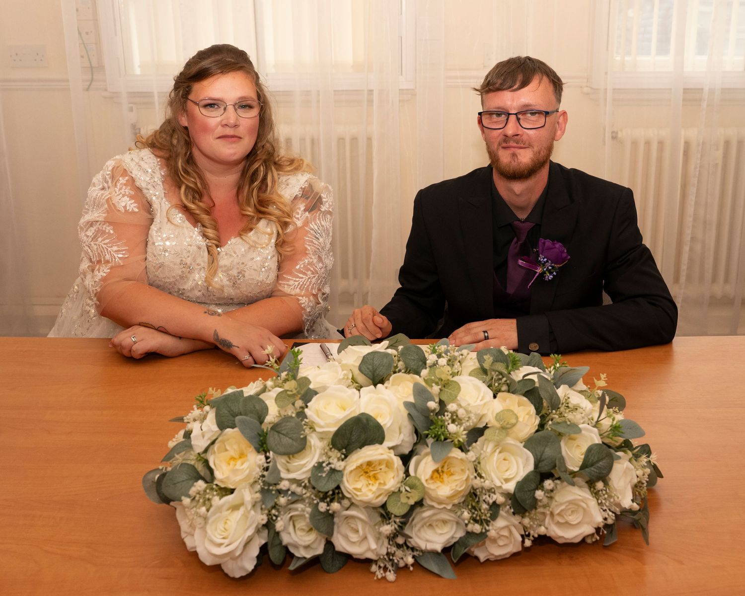 Wedding reception table setting with elegant white floral centerpieces and decorations.