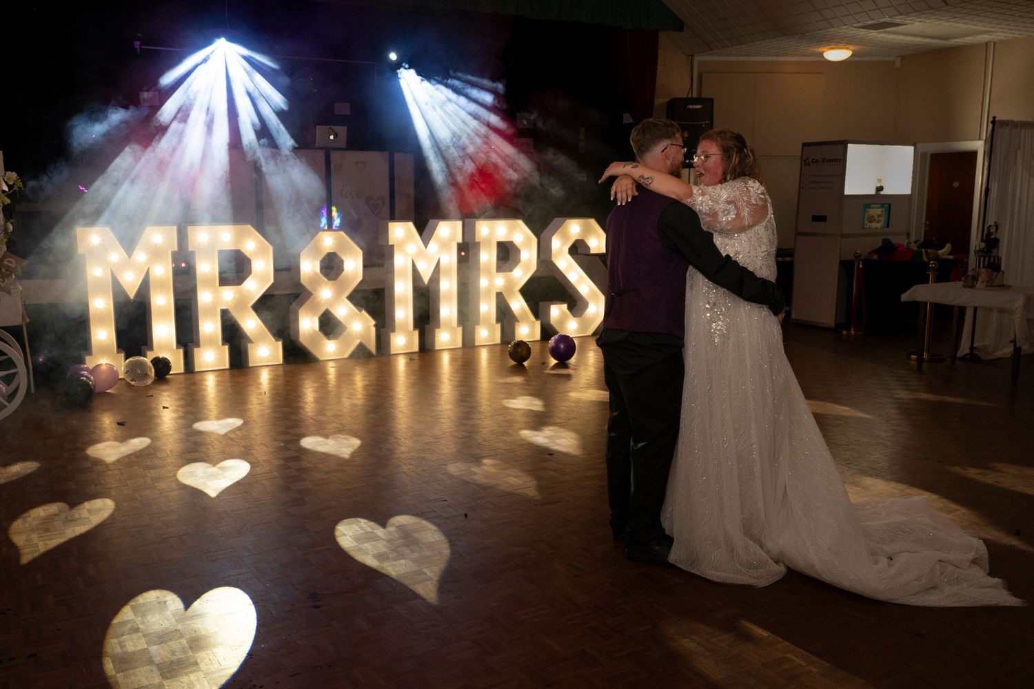 Illuminated 'MR & MRS' light-up letters at a wedding reception in a dark venue.